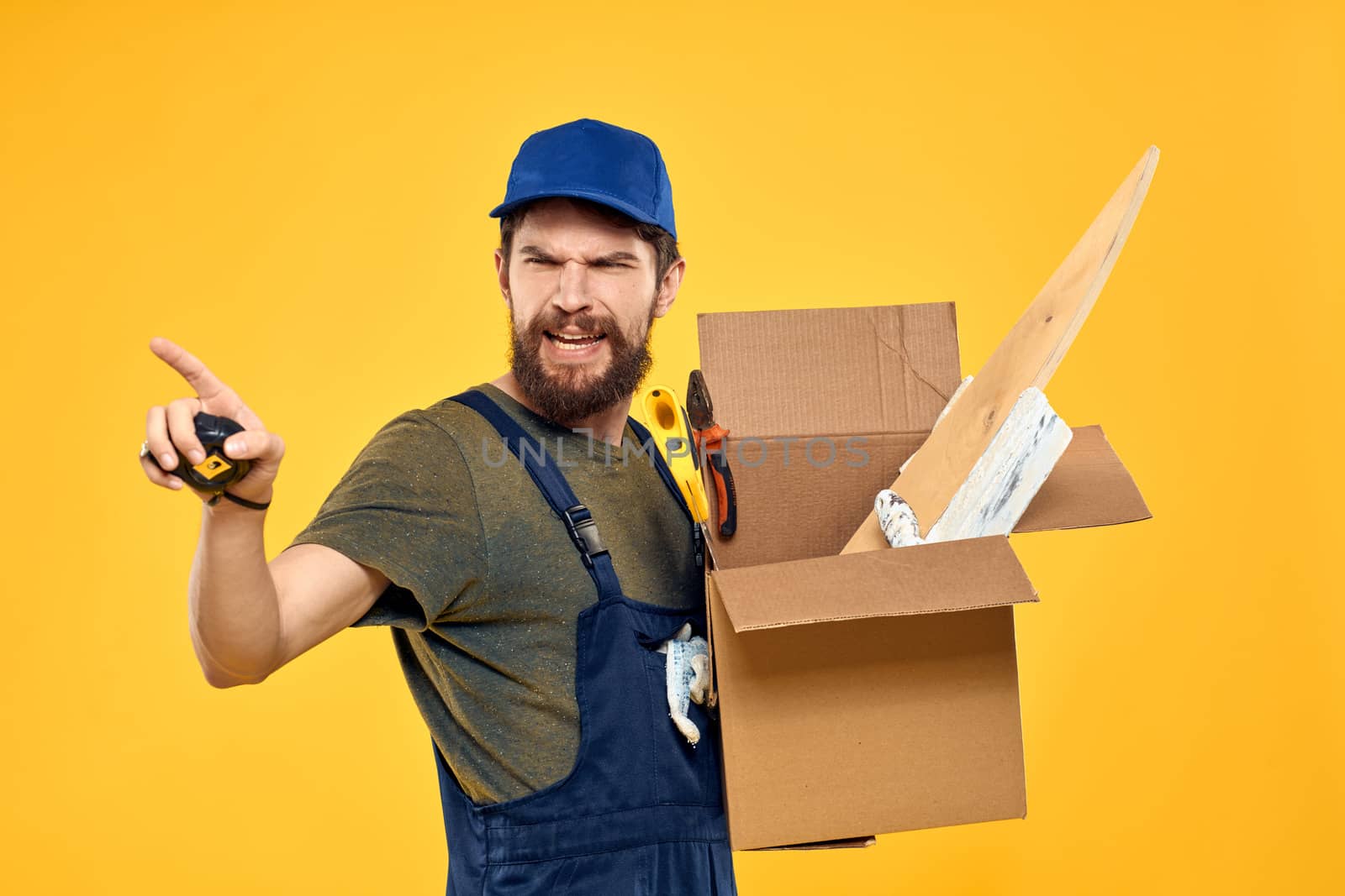 A man in a working form a box with loading tools yellow background. High quality photo