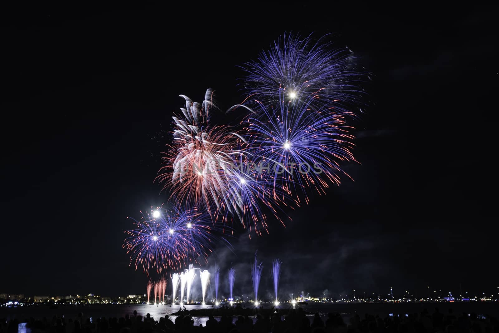 Scenic fireworks glowing in the night for the 14th of July celebrations in the harbor of Cannes, Cote d'Azur, France