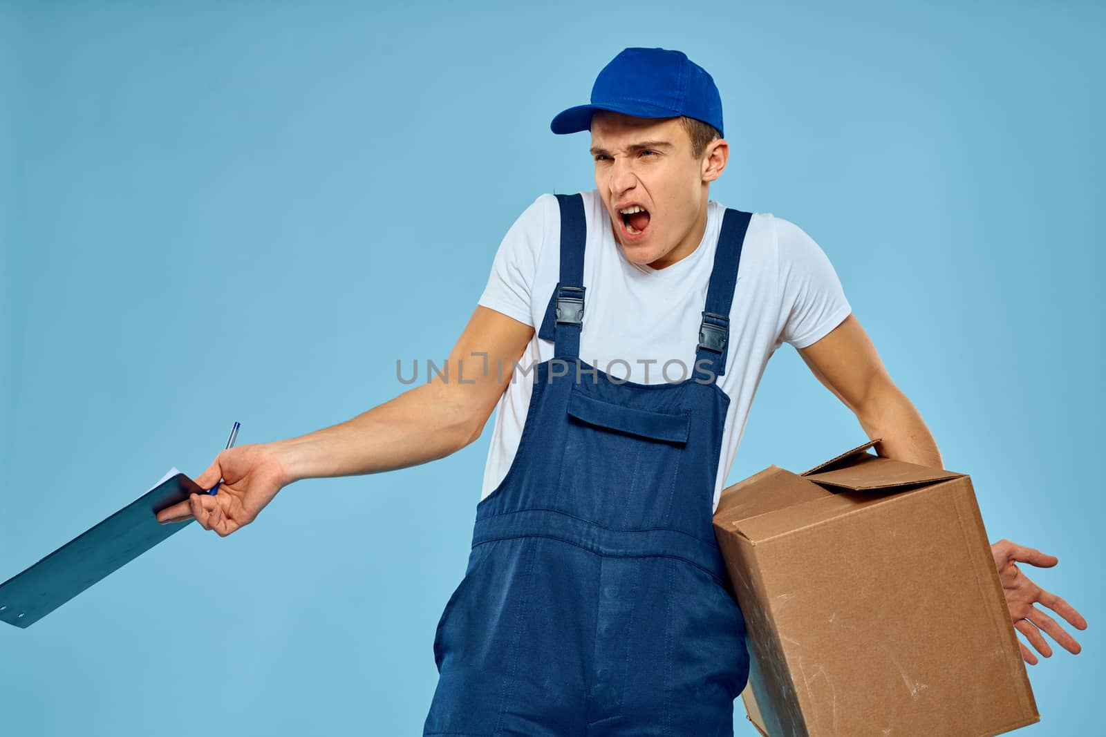 Man worker with cardboard box delivery loader lifestyle blue background by SHOTPRIME