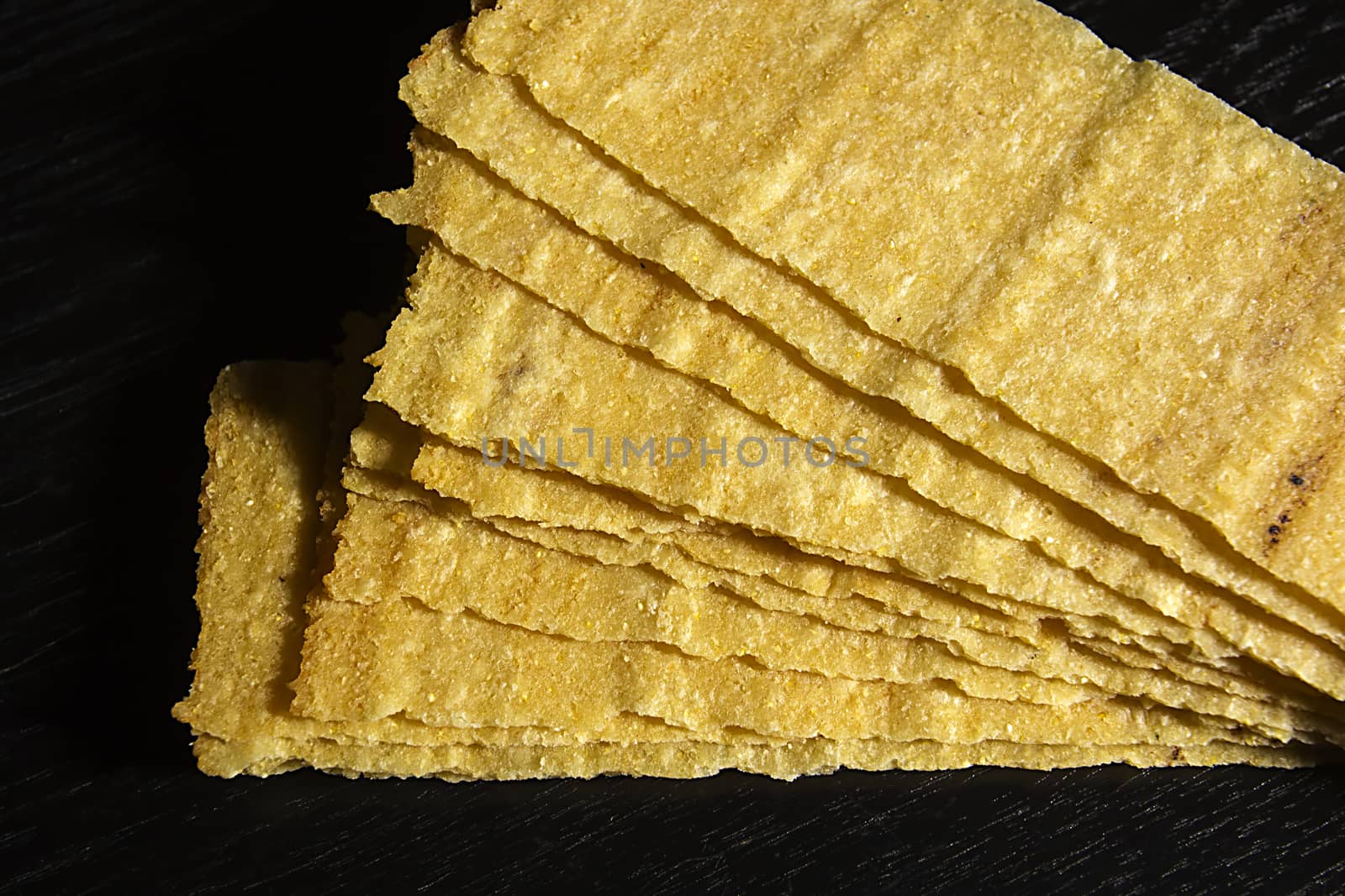 Rectangular potato chips on black wooden background