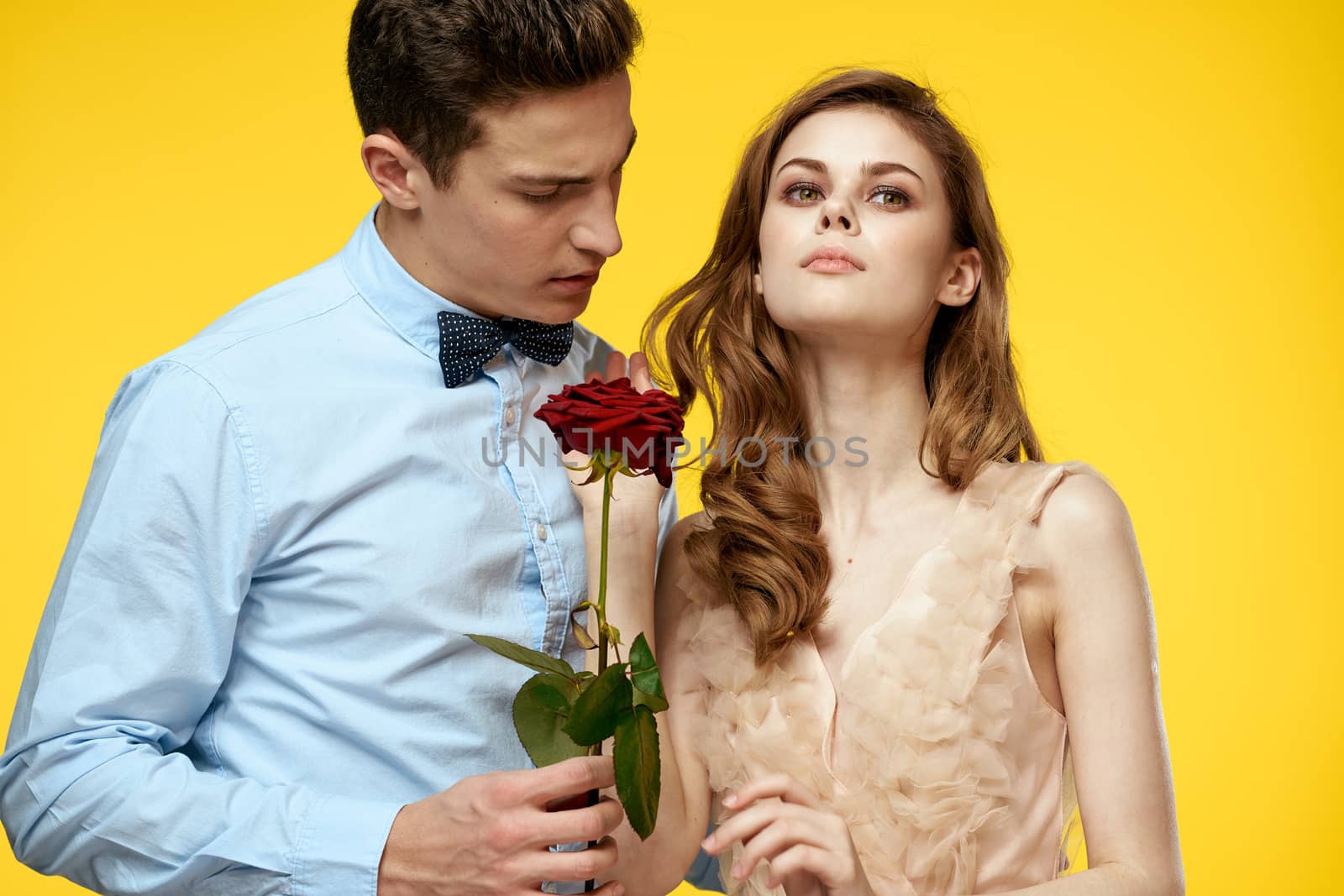 Enamored man and woman with red rose on yellow background cropped view close-up romance by SHOTPRIME