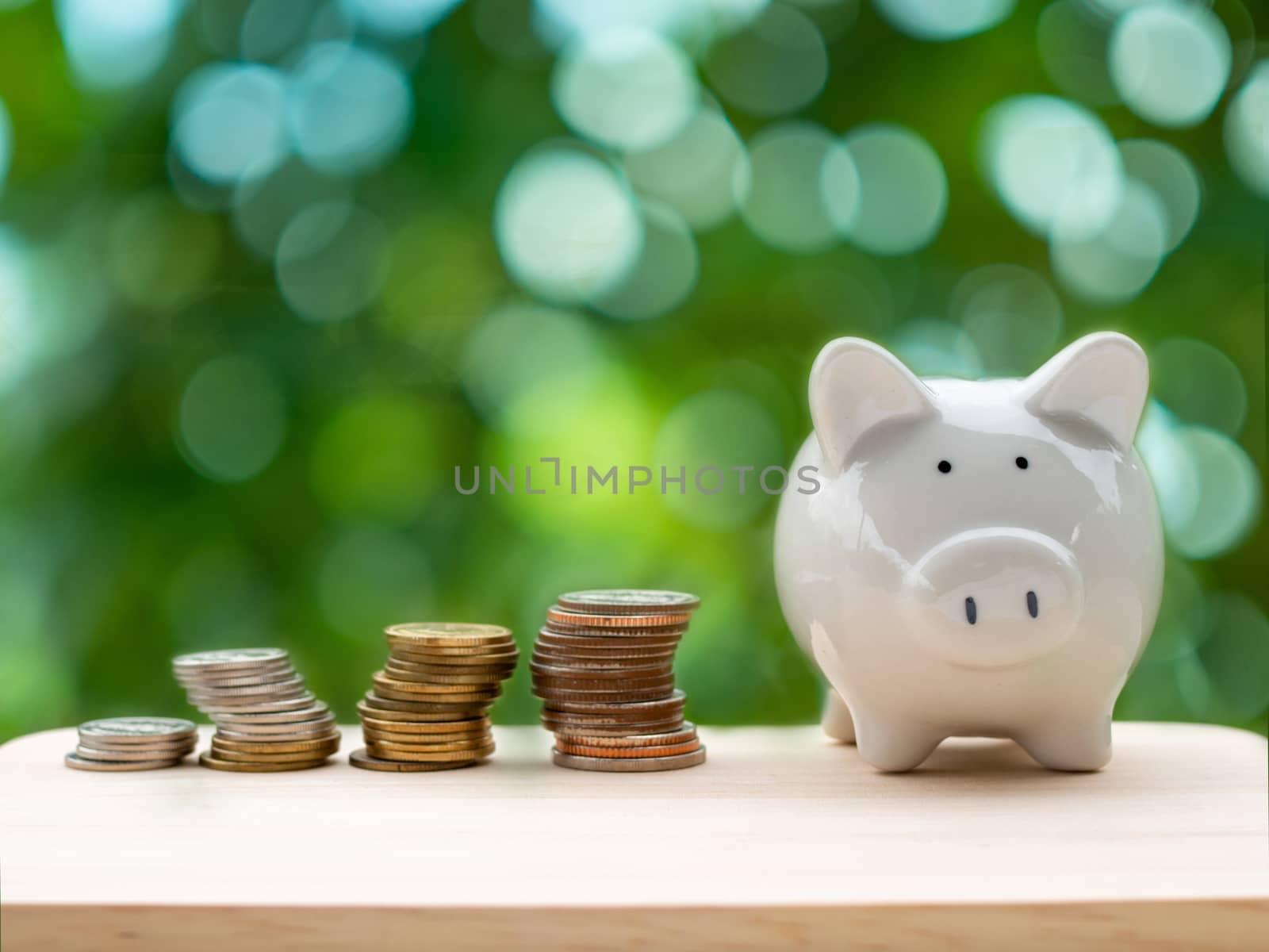 Piggy bank and silver coin placed on the wooden table. On natura by Unimages2527