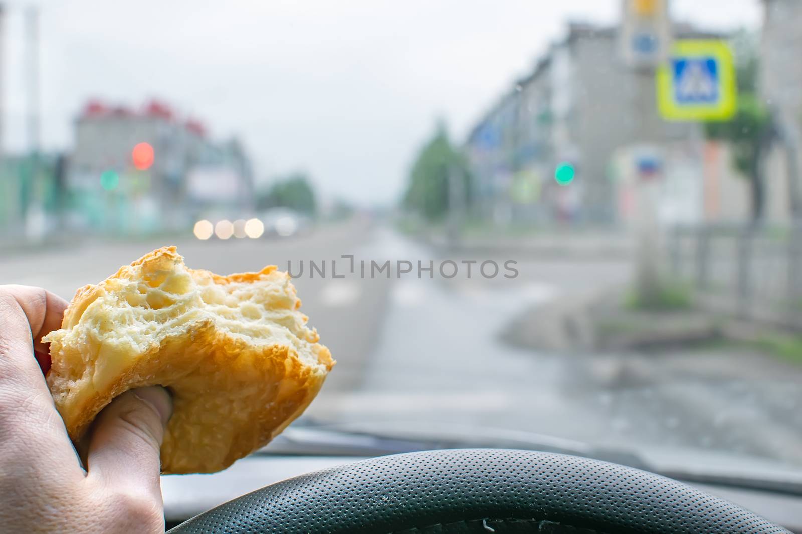 pie, bun, food in the hand of a driver at the wheel of a car by jk3030