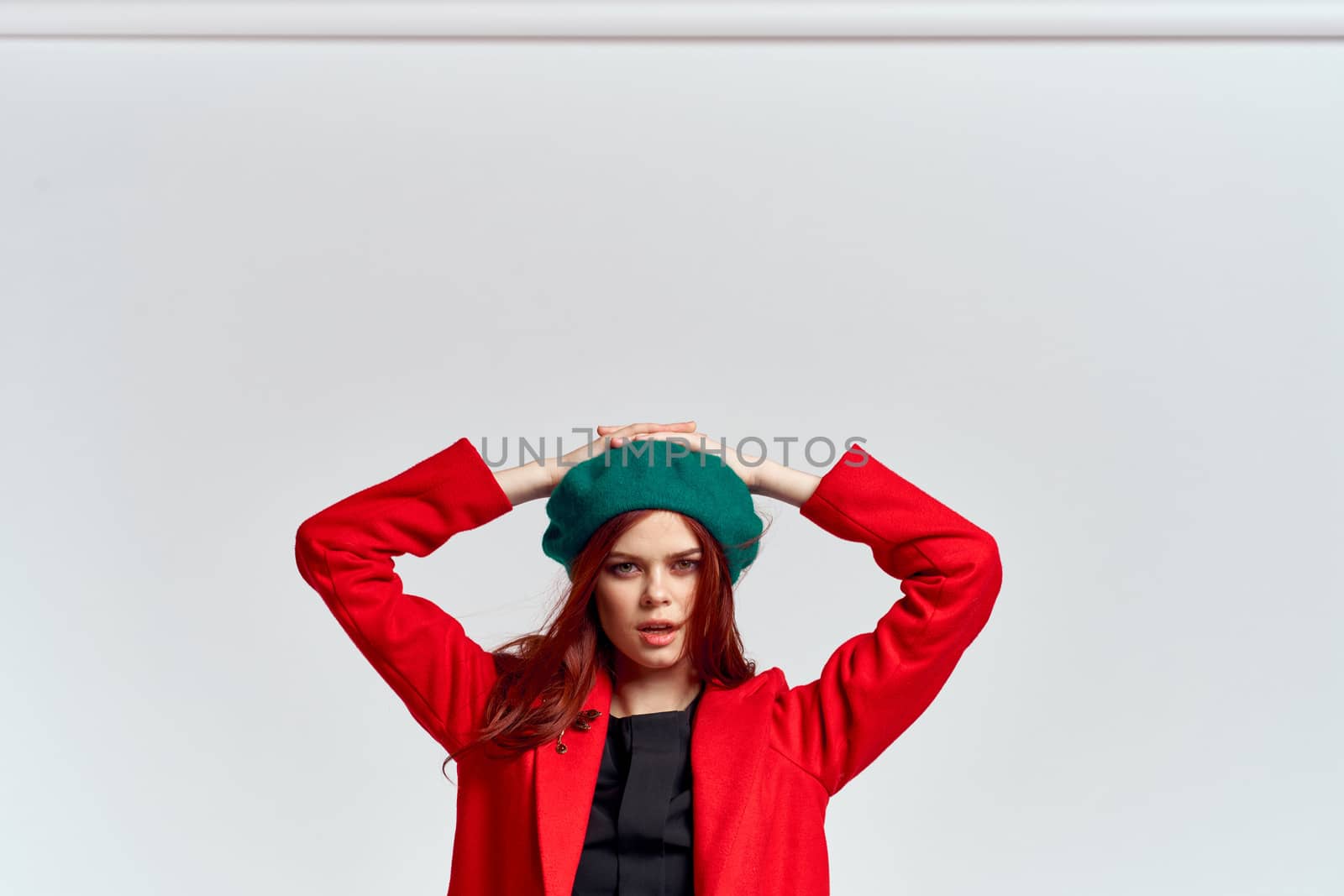 Woman in red coat and in green hat on isolated background cropped model with Copy Space emotions. High quality photo