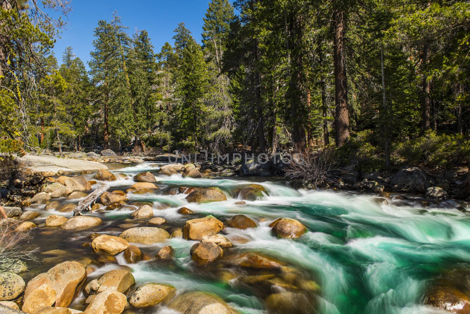 Wild Merced river with turquoise water and many boulders in Yosemite National Park. Long exposure. California, USA