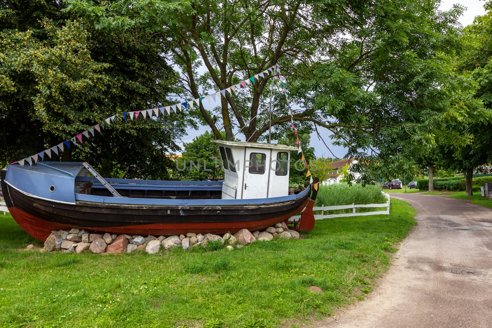 Old multi colored wooden fishing trawler on a meadow by reinerc