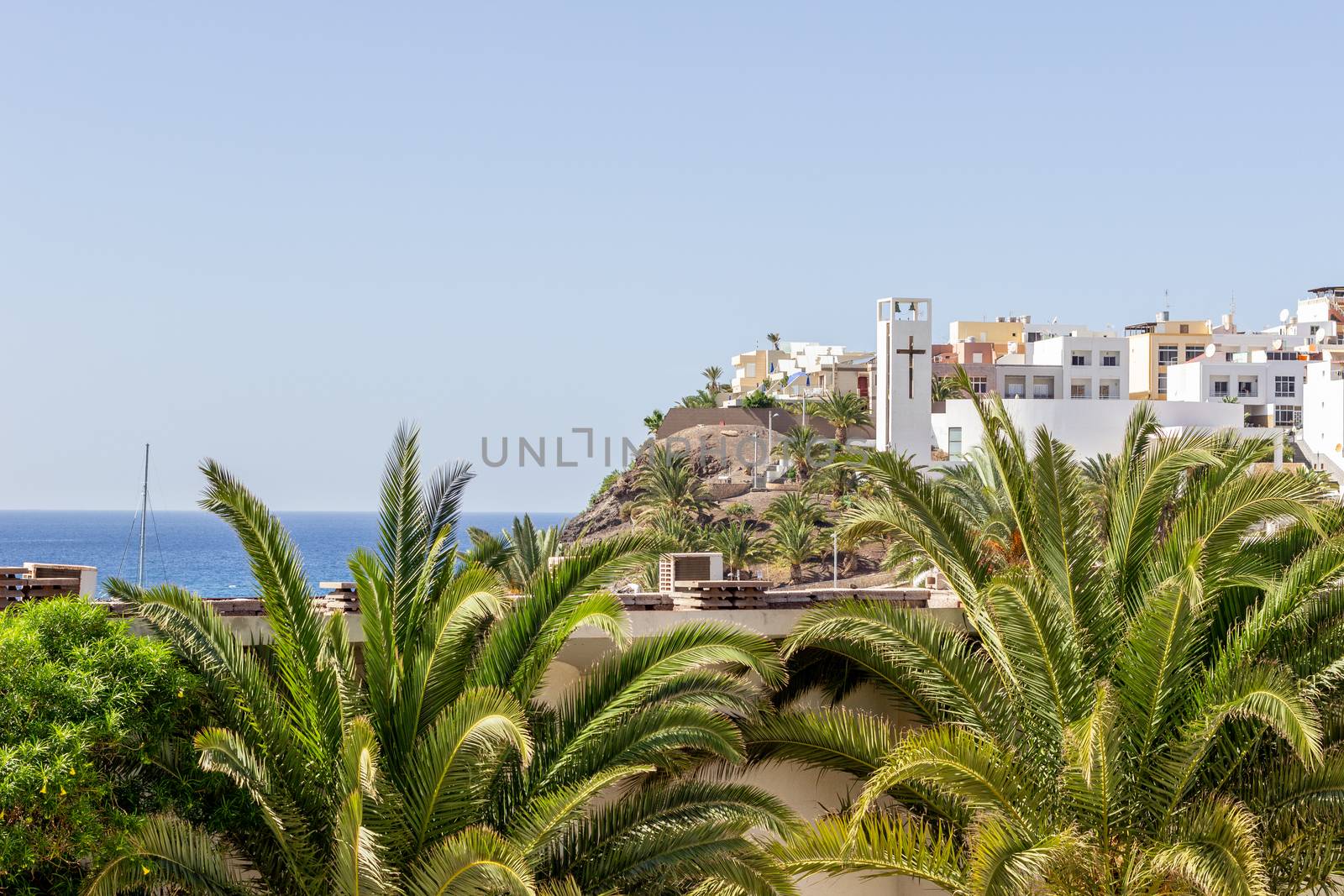 Scenic view at Morro Jable on canary island Fuerteventura, Spain with palm trees and white buildings in the foreground and the atlantic ocean in the background