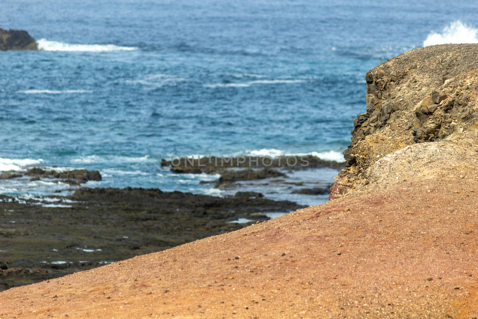 Scenic view at the coastline in the natural park of Jandia (Parque Natural De Jandina) on canary island Fuerteventura, Spain with gravel, lava rocks and rough sea with waves