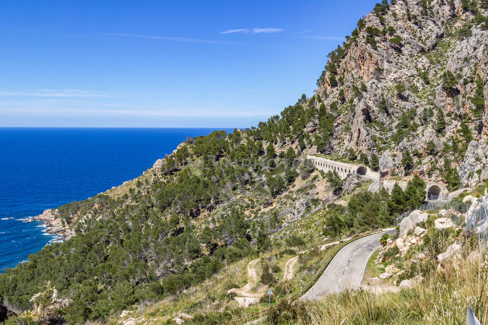 Scenic view in summer at the north coast of Mallorca with mountain in foreground, blue water and blue sky in background 