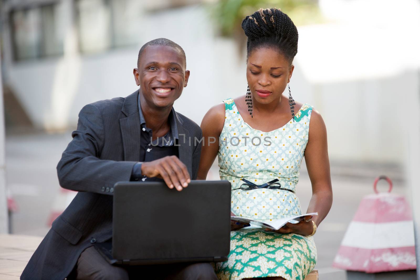 Business people sitting out laughing and working together on a laptop.