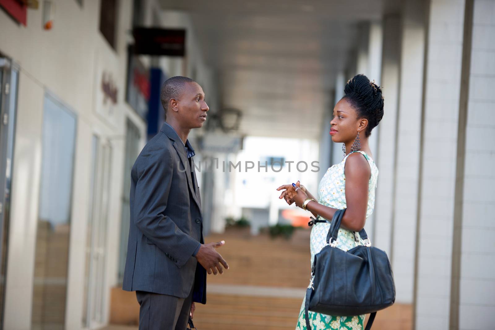Businessman and businesswoman discussing work standing face to face and speaking with gestures.