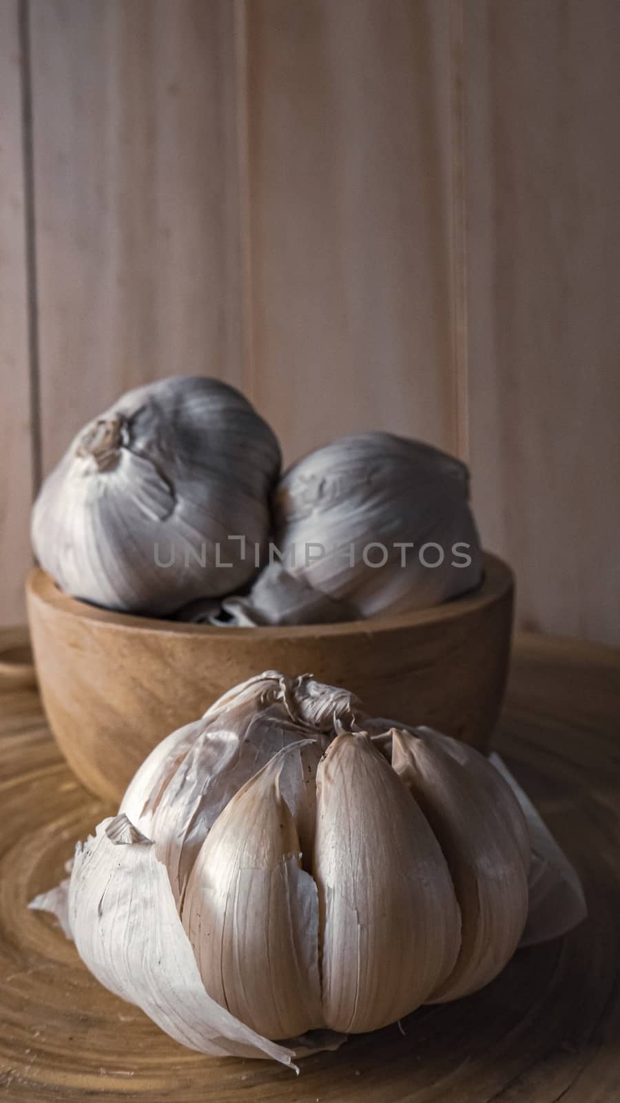 The garlic in wood bowl  on wood table for food content.