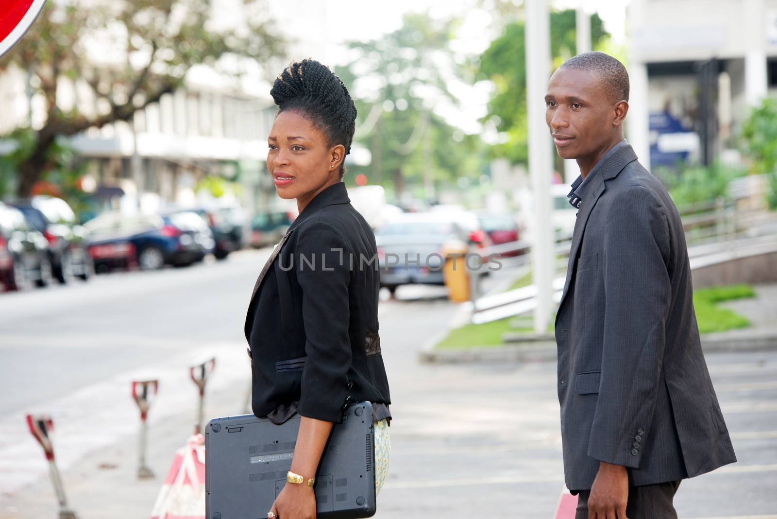 business partners walking together outside with a laptop in the young woman's hand.