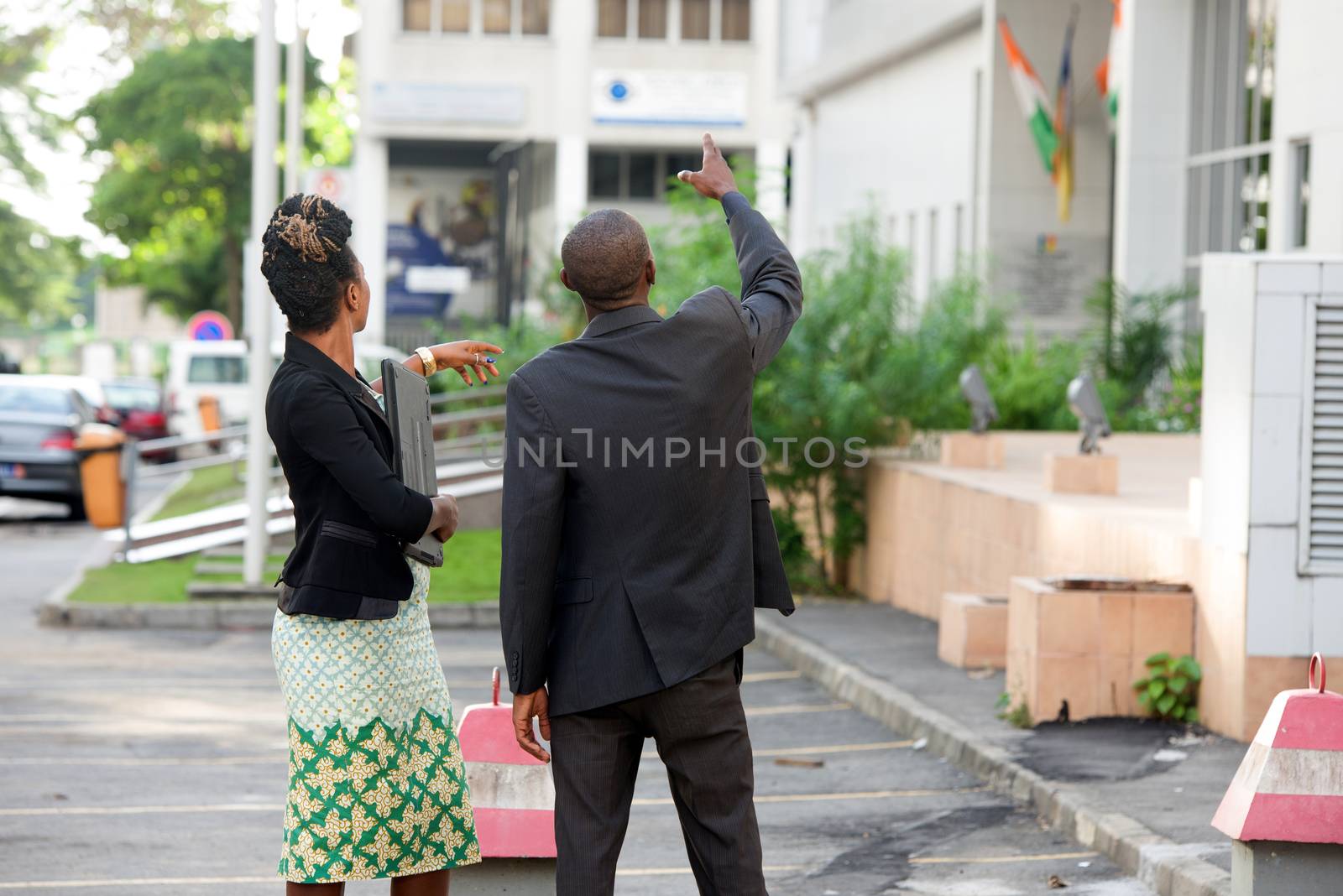 young businessman shows something to his colleague in front of a building.