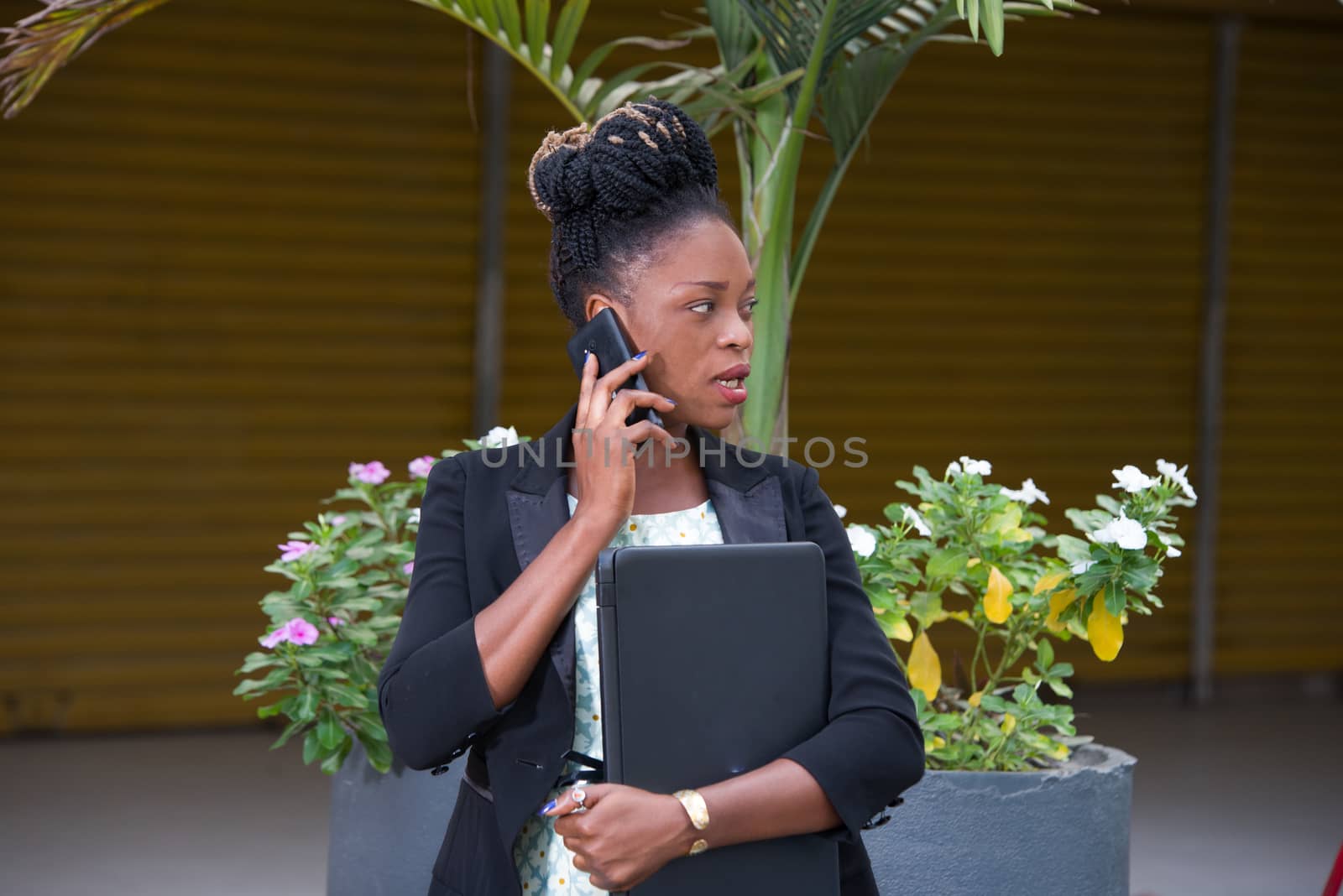 young businesswoman standing calling on the phone and holding a laptop