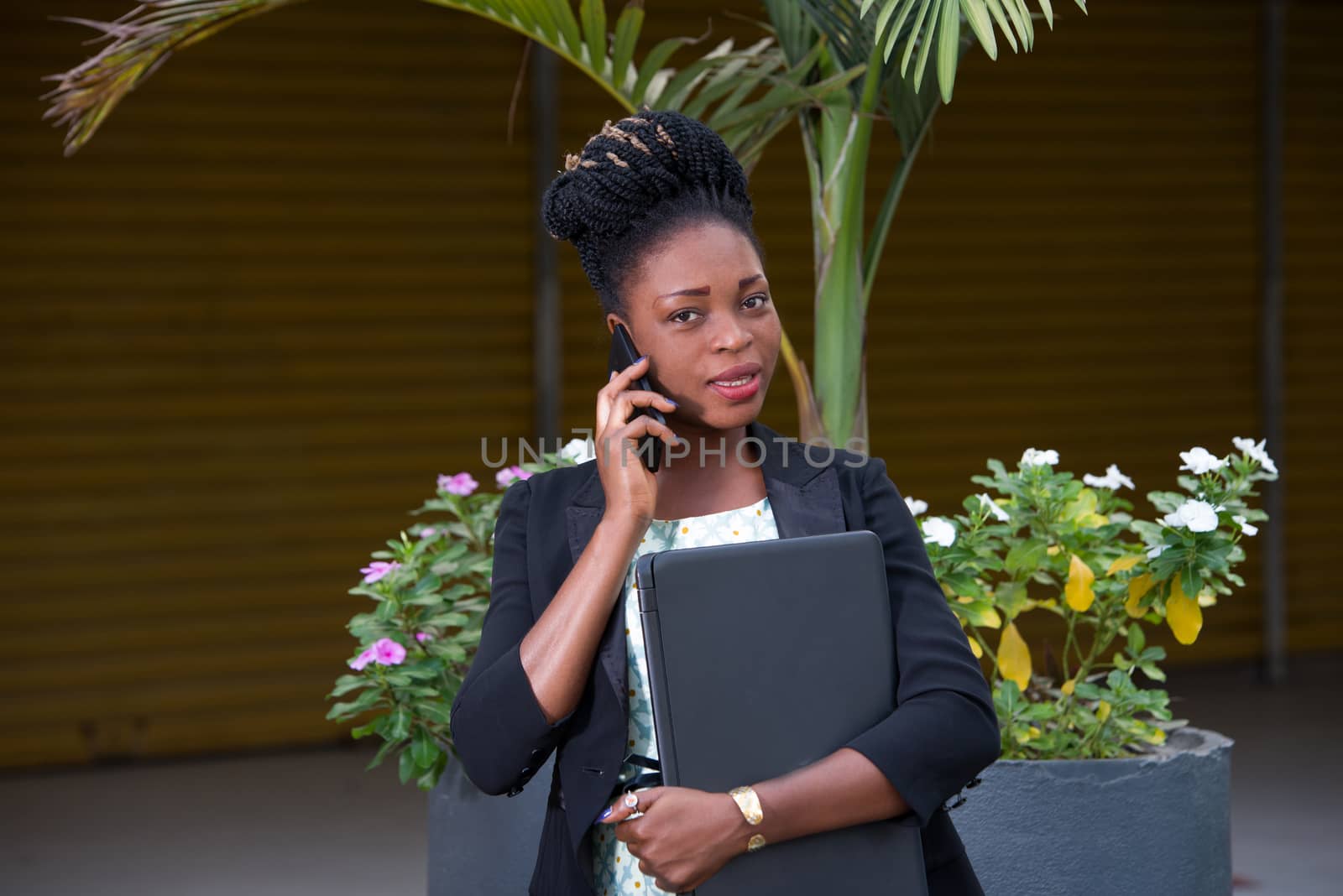 young businesswoman standing calling on the phone and holding a laptop