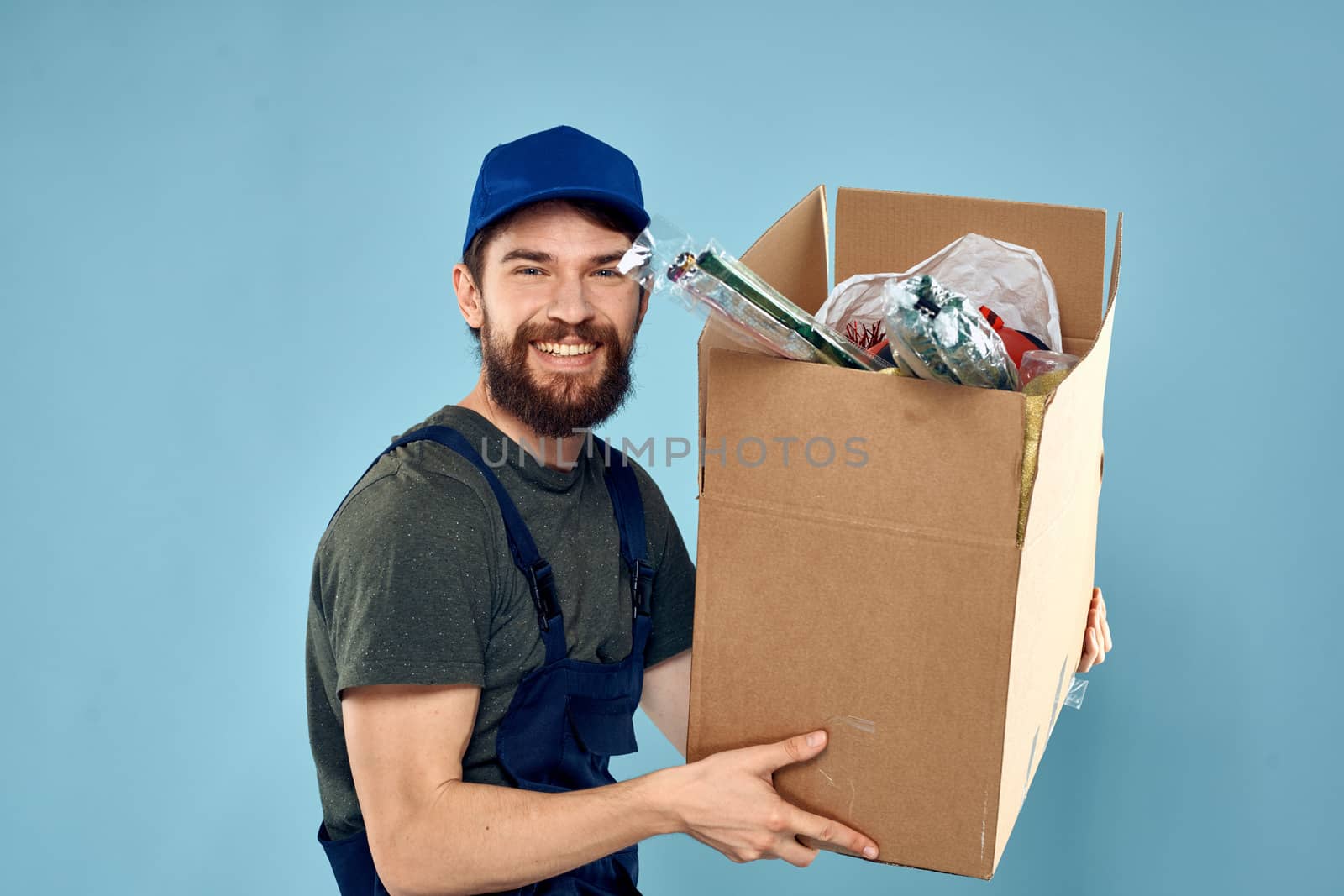 working man boxes in hands delivery service packaging lifestyle blue background by SHOTPRIME