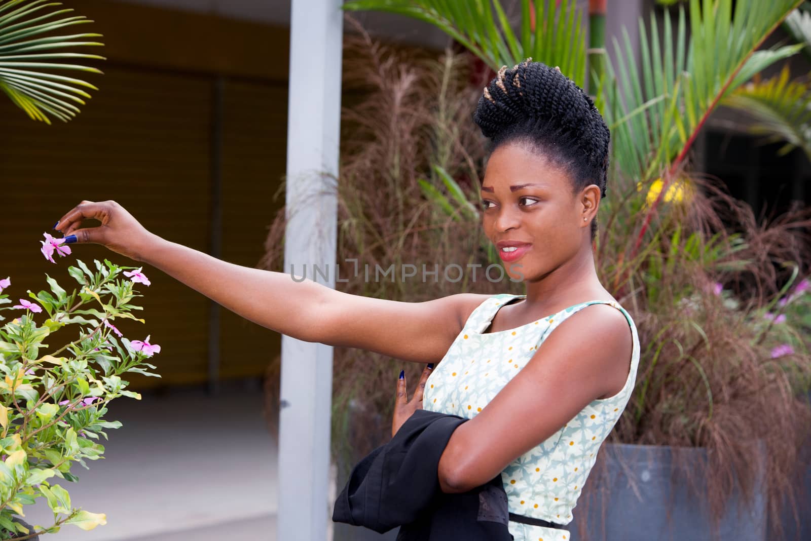 happy young woman pausing alone in front of a flower pot in the street after work
