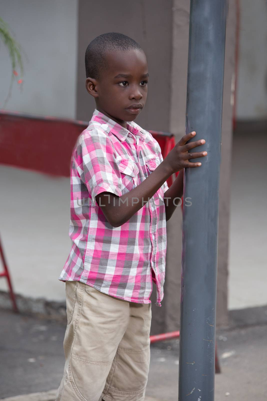 child, sad and lonely standing in the street against a metal