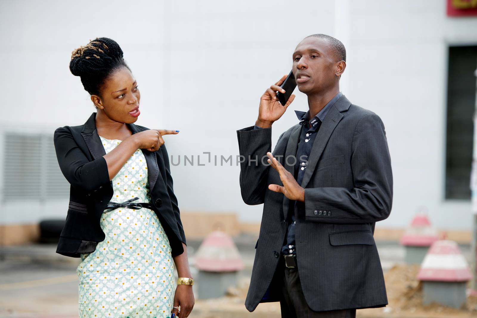 woman having a serious argument against a businessman talking on the phone outdoors