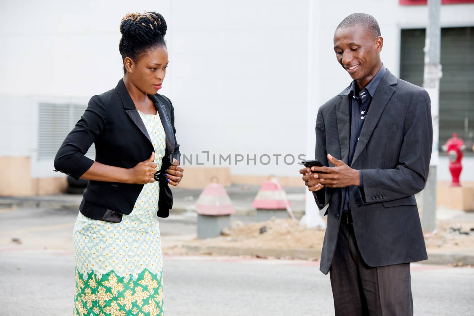 businessman using a mobile phone next to a businesswoman on the move walking in the street