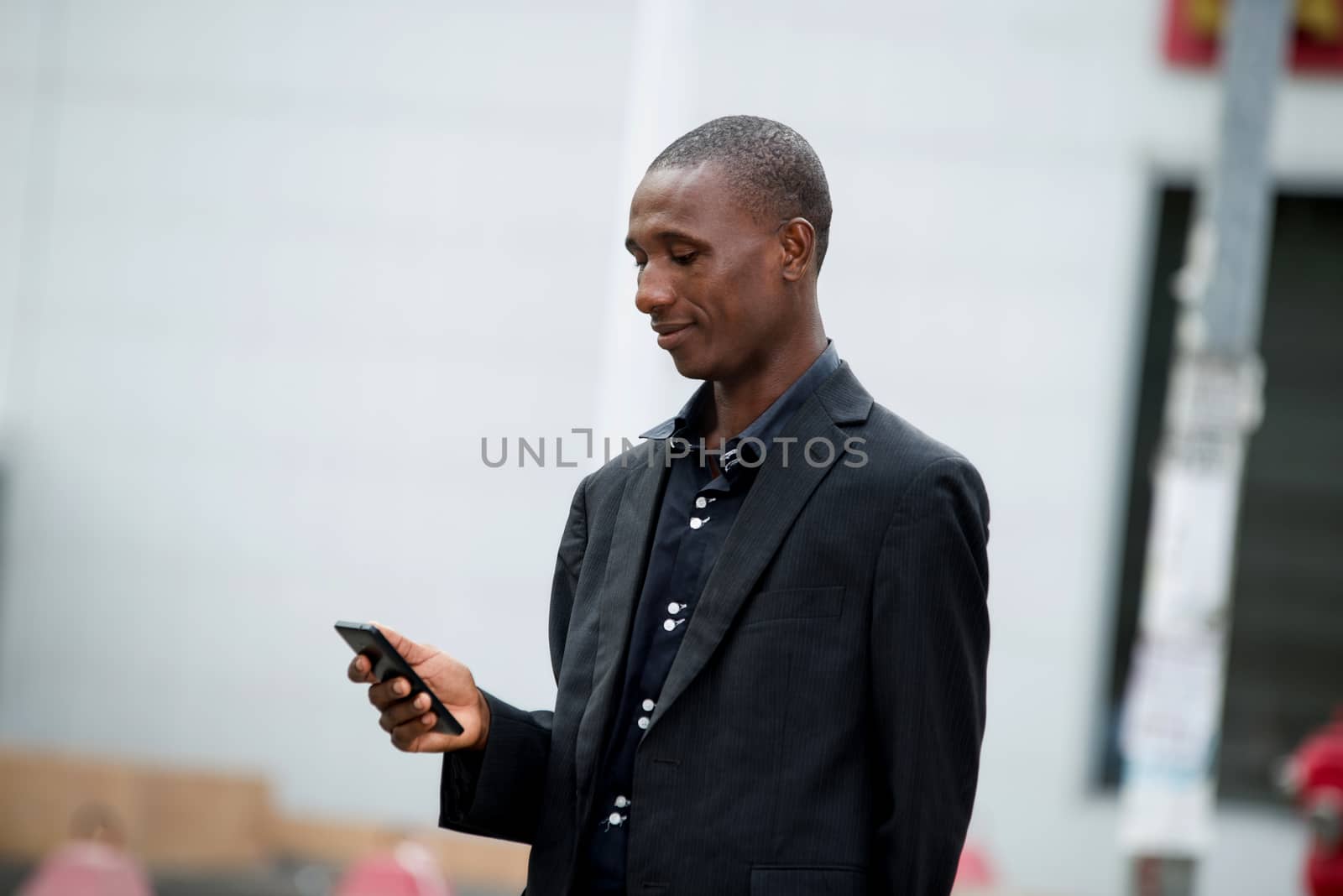 Image of a businessman in a suit standing on the street and checking his mobile phone