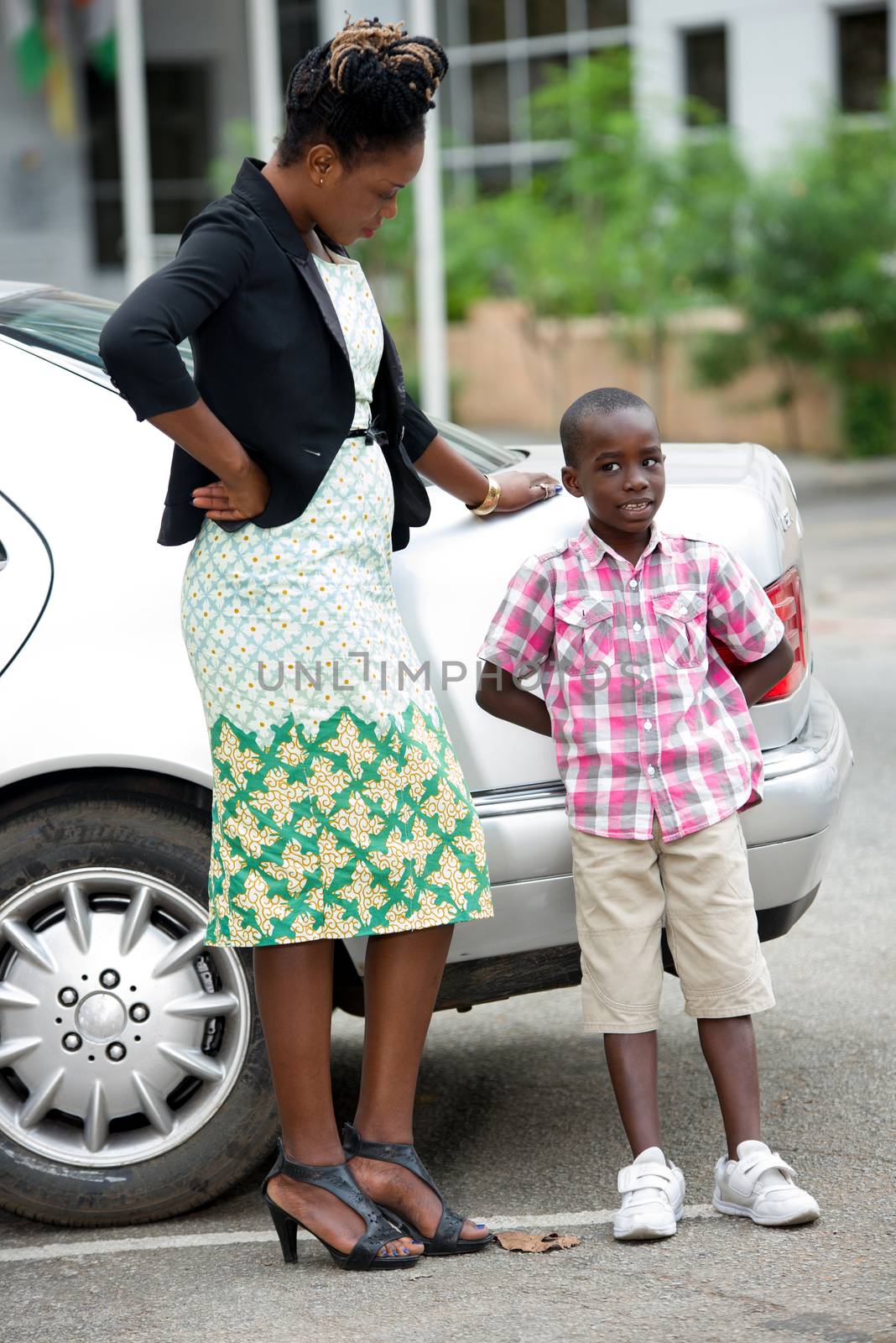 young businesswoman standing near a car and talking with her son