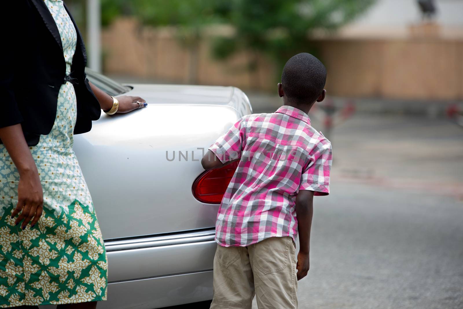 child standing back from a car and looking away