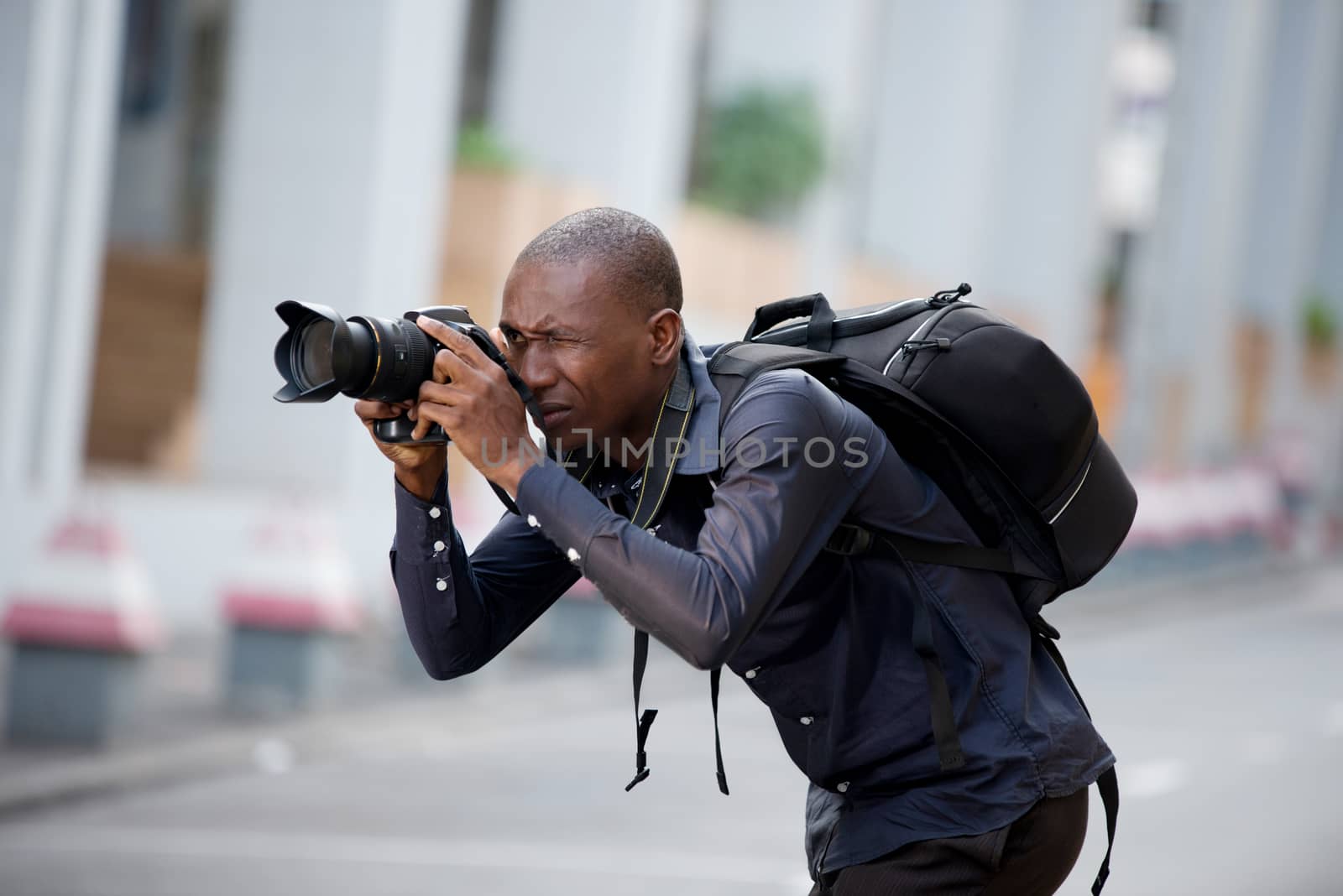 Young man photographer takes a picture of the city and its buildings. Concept of travel and tourism.