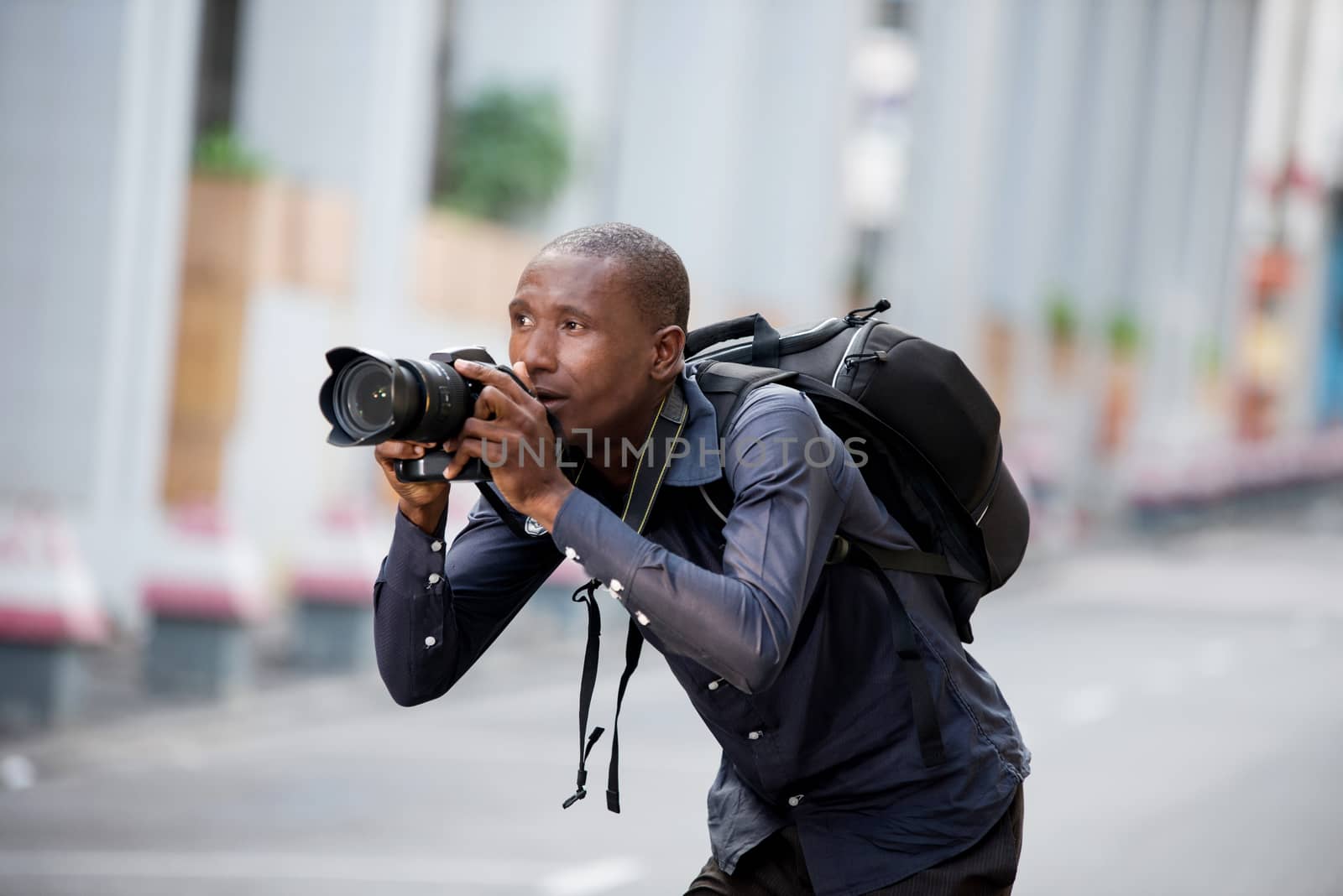 Young man photographer takes a picture of the city and its buildings. Concept of travel and tourism.