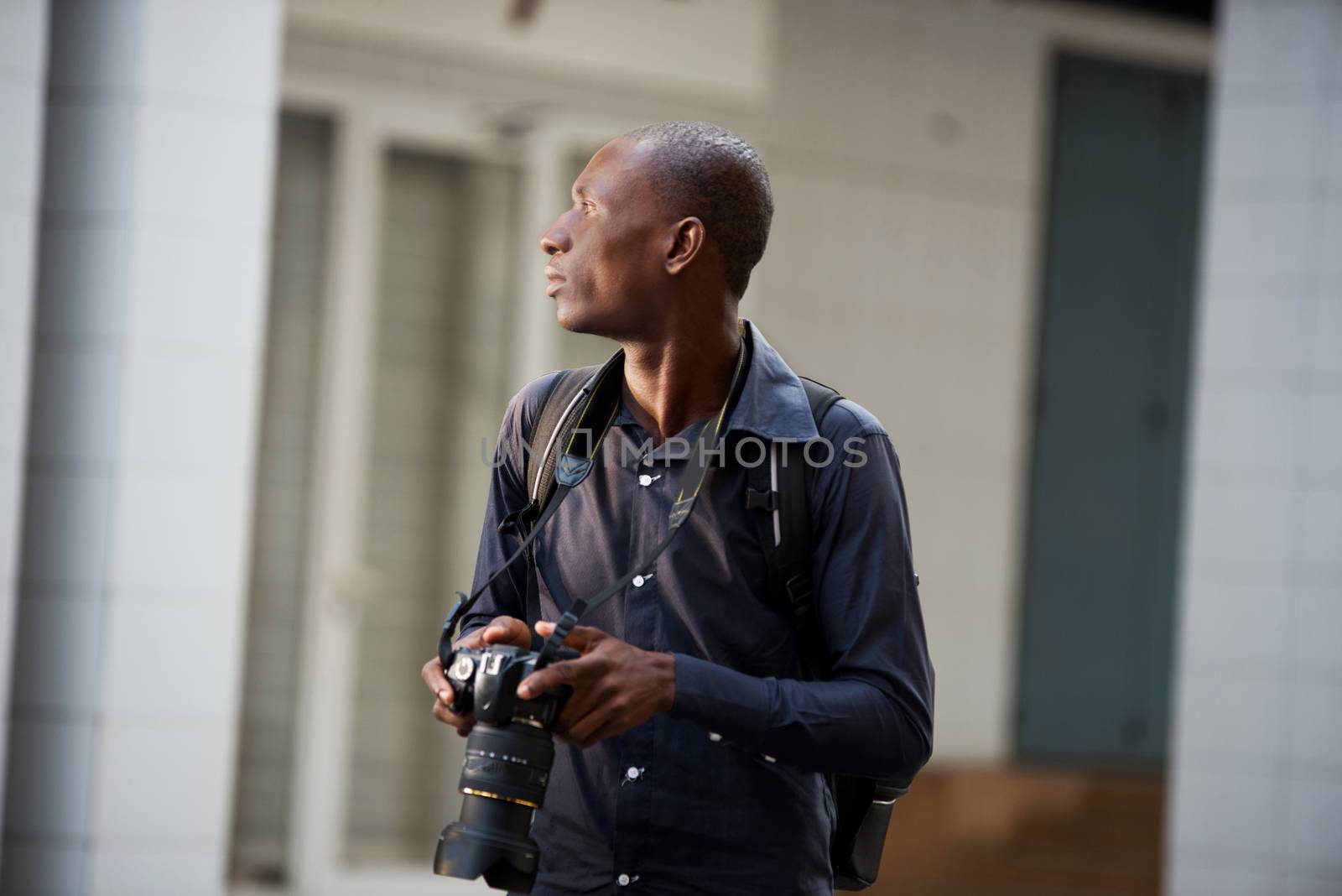 Portrait of smiling young man with camera in hand walking the city to take pictures