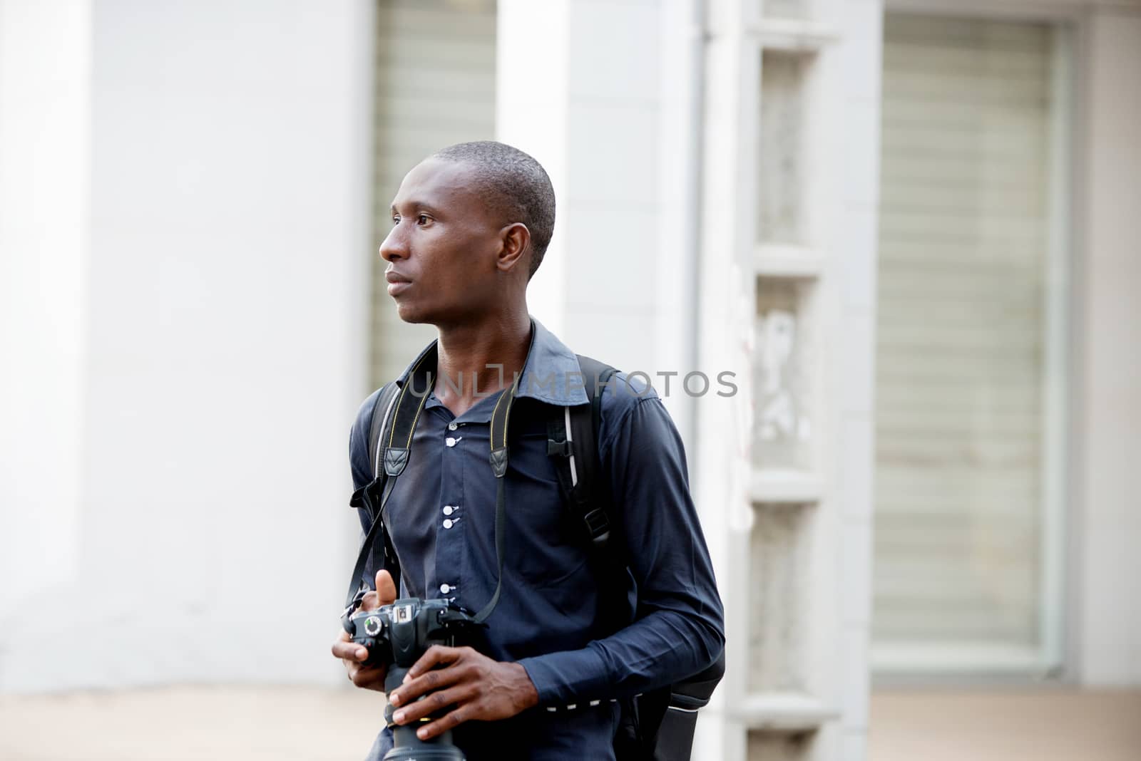 Young tourist walking with a camera at the neck in the city looking for a pretty place to photograph