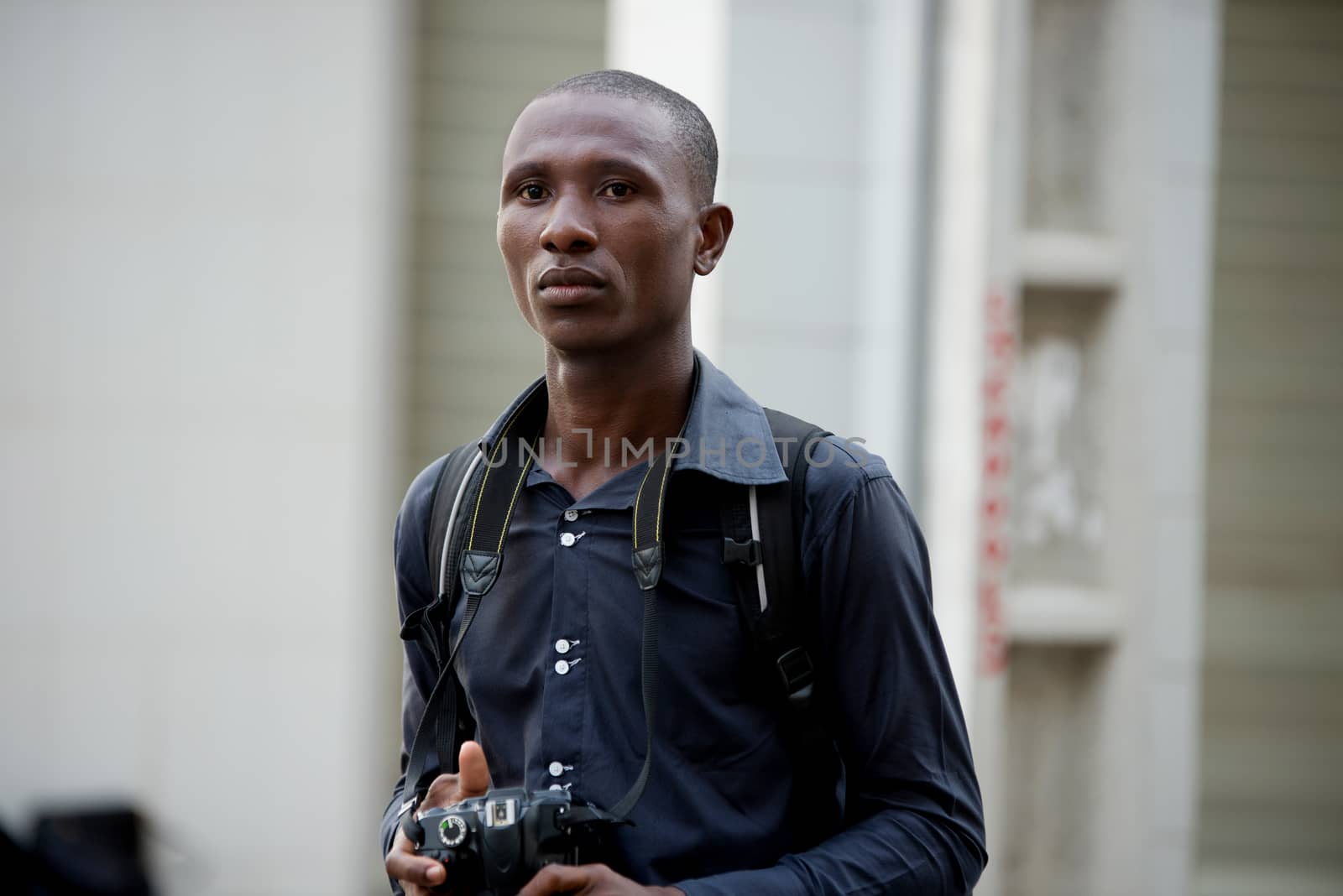 Young tourist walking with a camera at the neck in the city looking for a pretty place to photograph