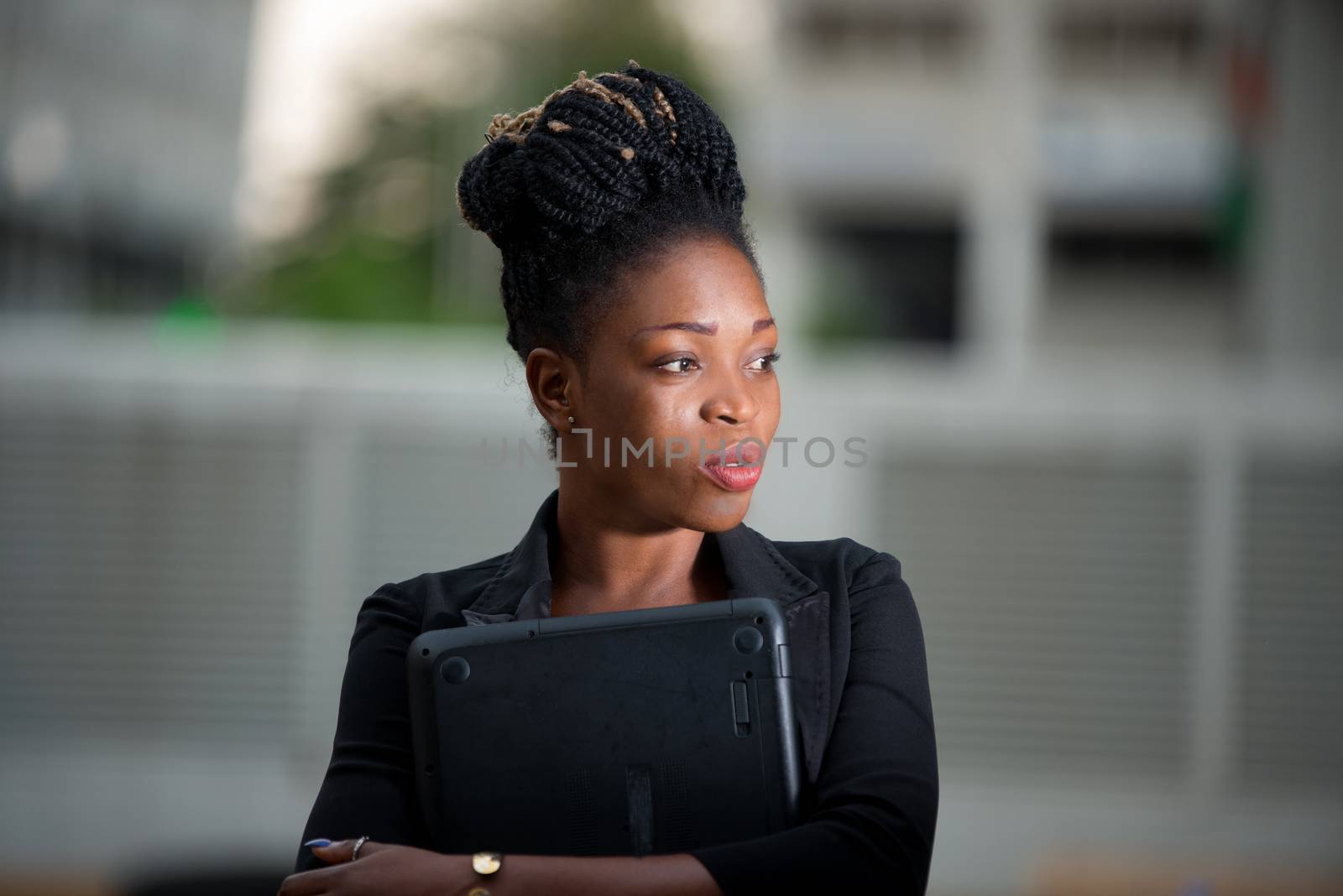 businesswoman standing outside and pensive holding a laptop against her chest