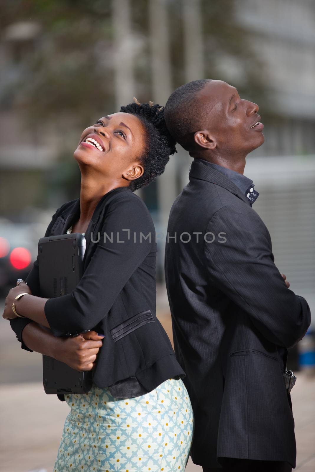 businesswoman and businessman, happy team standing together outdoors giving themselves back and looking at the sky