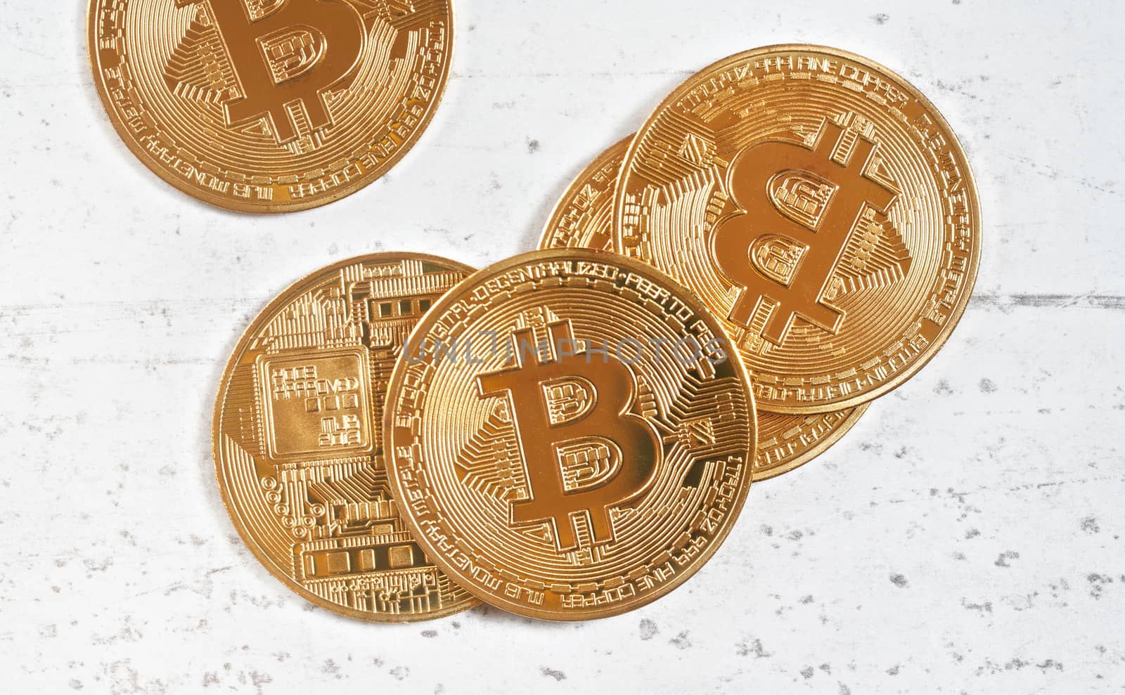 Top down view, golden commemorative btc - bitcoin cryptocurrency - coins scattered on white stone board, closeup detail.