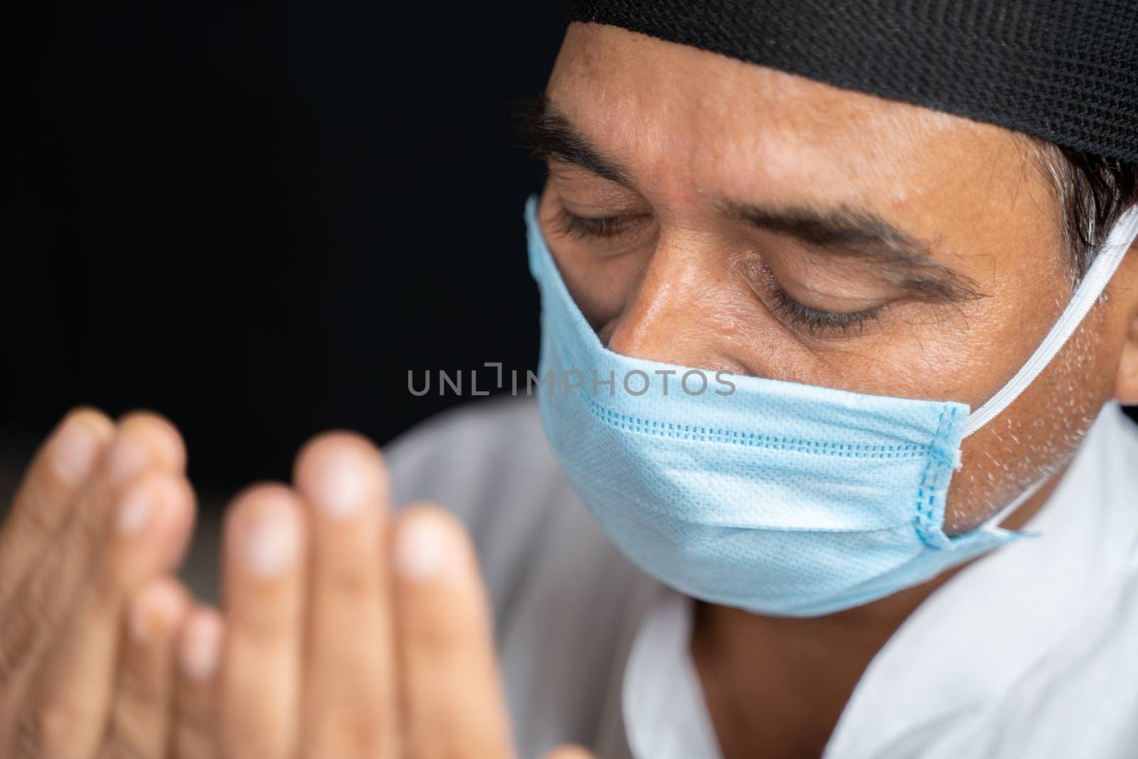 High angle view close up shot of muslim man in medical mask preforming Salah or prayer by closing eyes. by lakshmiprasad.maski@gmai.com