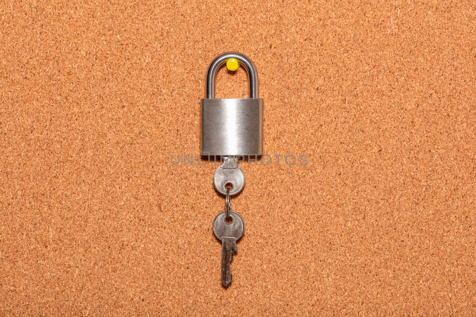 Closed padlock with keys hanging from it on an empty corkwood notice board in business office. Safety and security reminder, business closure, business for sale concepts.