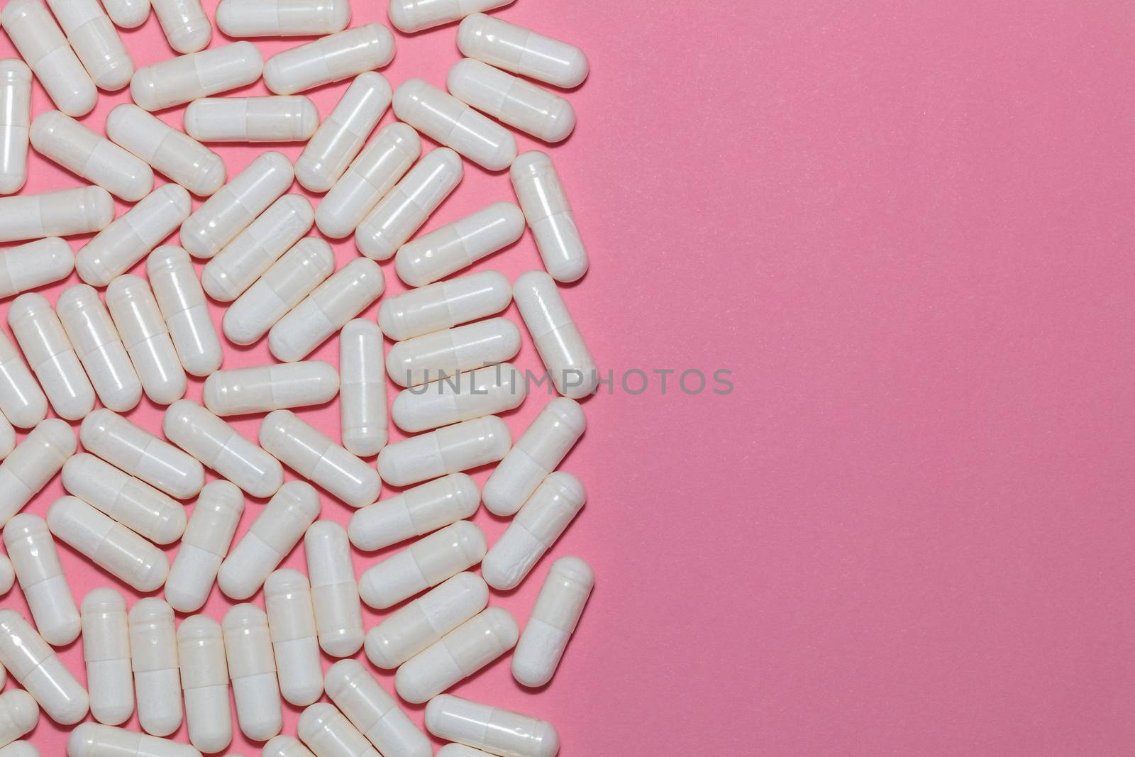 Top view of white pills on pink background with copy space. Healthcare, medical and pharmaceutical concept. by DamantisZ