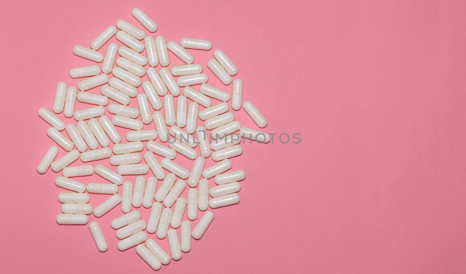 Top view of white pills on pink background with copy space. Healthcare, medical and pharmaceutical concept. by DamantisZ