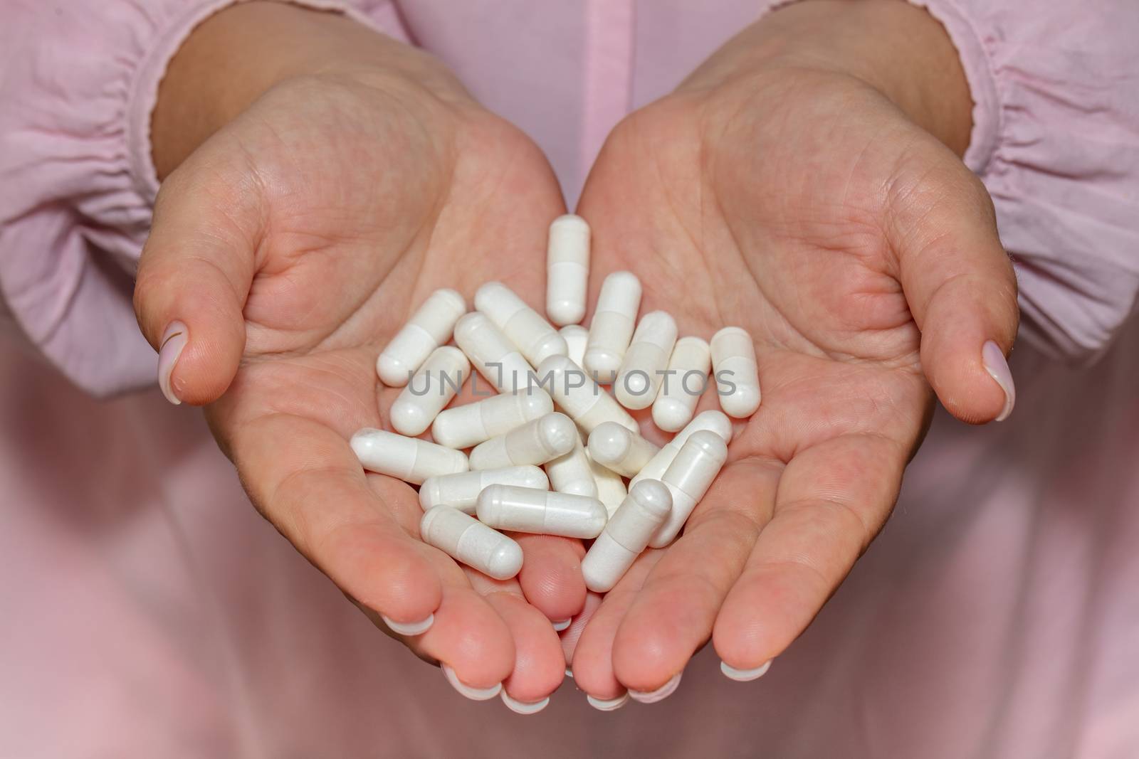 High angle closeup shot of female hands holding a bunch of white pills. Healthcare, medical and pharmaceutical concept.