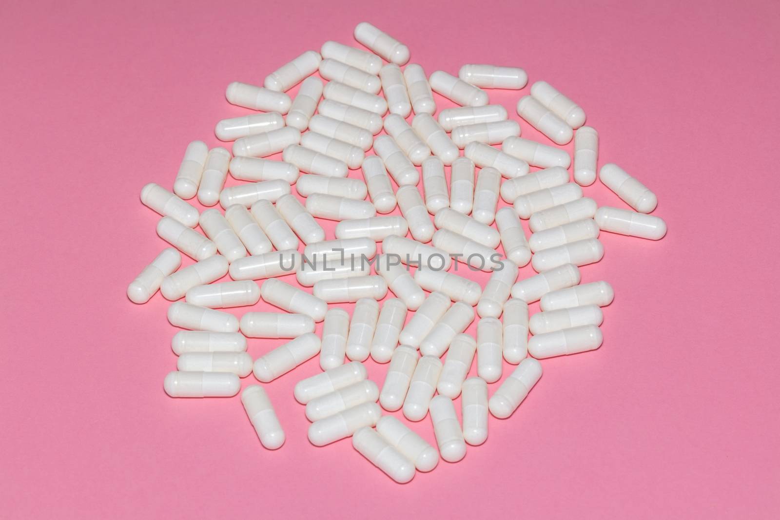 High angle shot of white pills on pink background. Healthcare, medical and pharmaceutical concept.