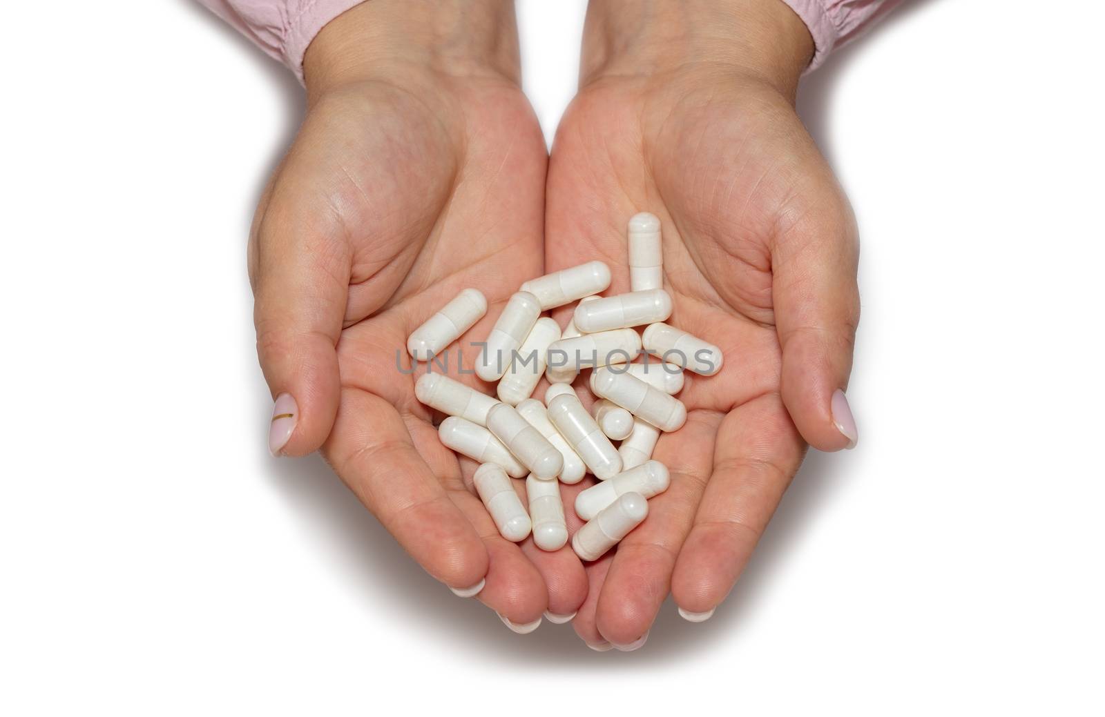 Top closeup shot of female hands holding a bunch of white pills on white background. Isolated. Healthcare, medical and pharmaceutical concept. by DamantisZ