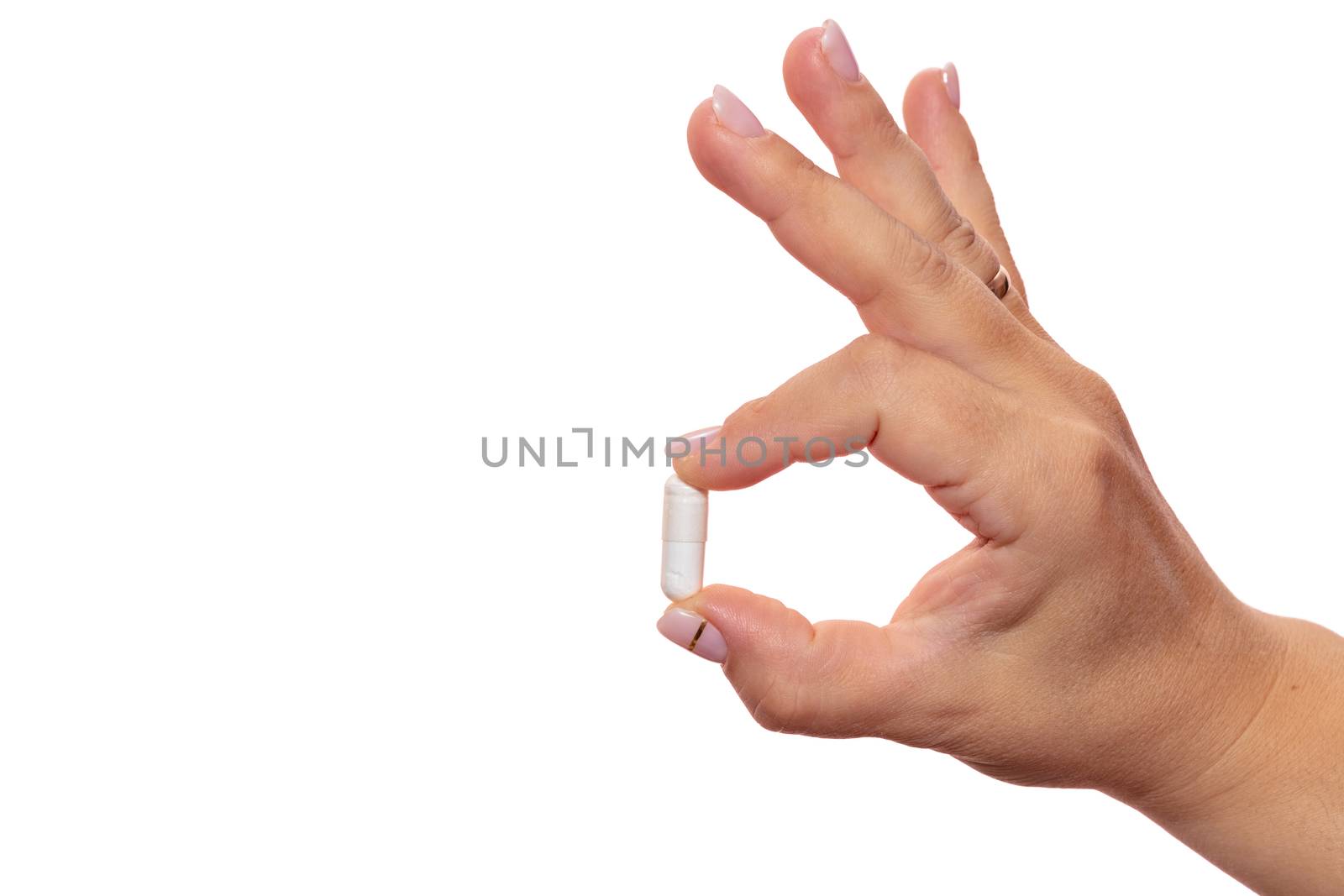 Female hand holding a white pill. Isolated on white background. Close up shot. Healthcare, medical and pharmaceutical concept.