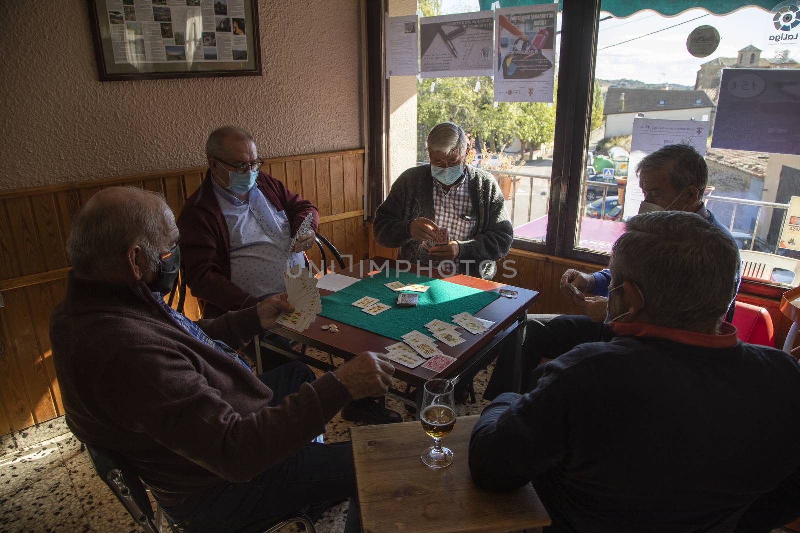 A group of pensioners, with face masks, bet and play cards, Spain by alvarobueno