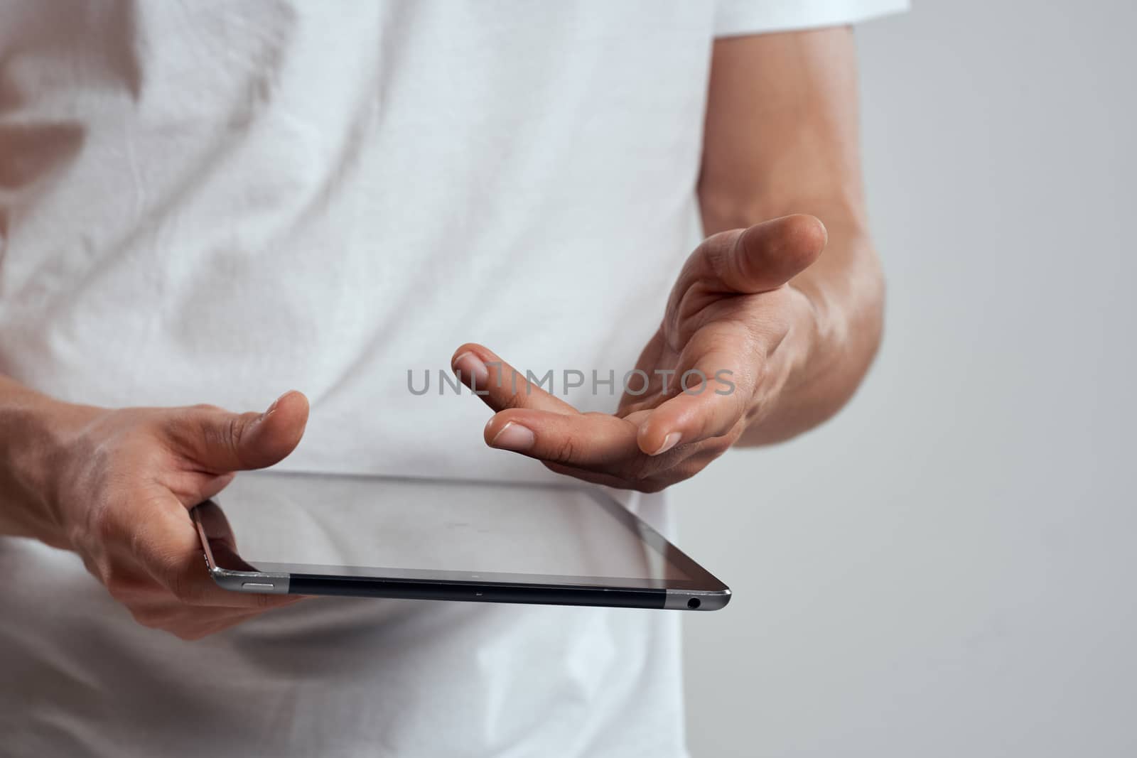 Tablet with a touch screen on a light background male hands white t-shirt cropped view by SHOTPRIME