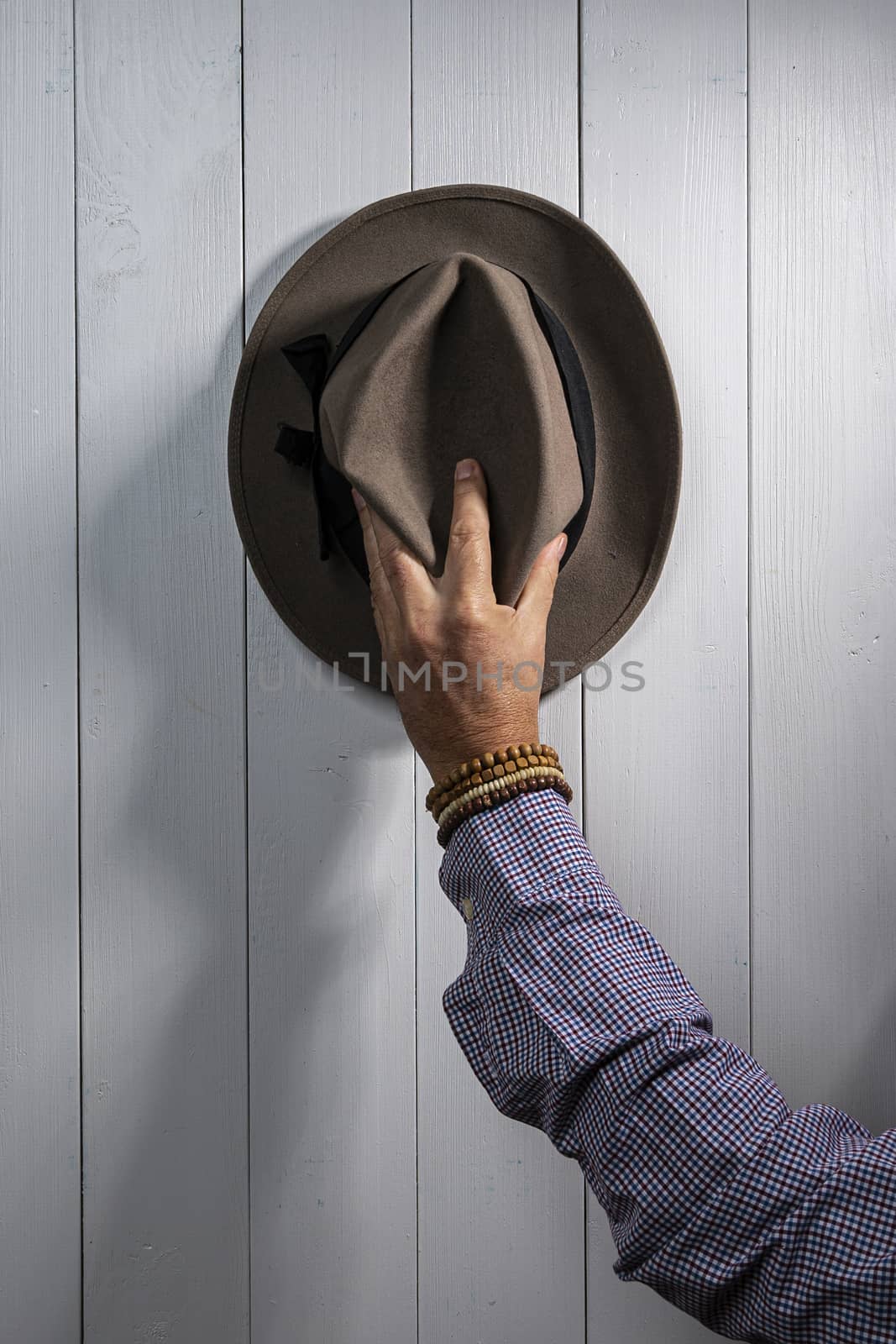 an old hat hanging on a white wooden wall