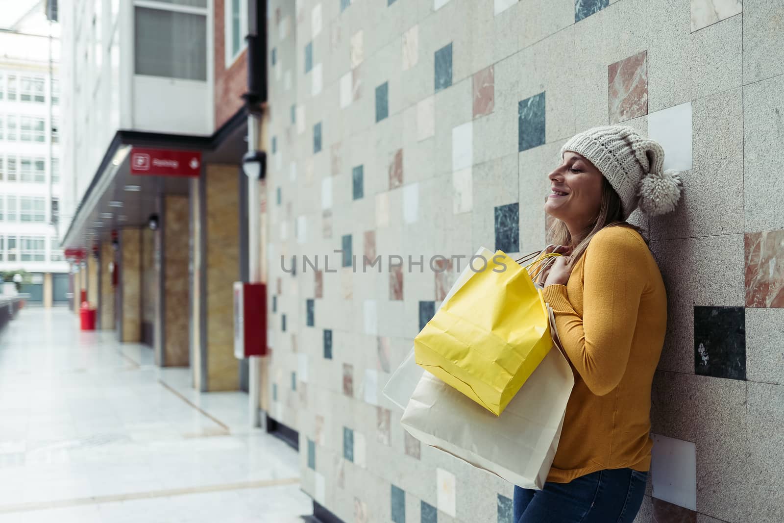 Woman in wool hat smiling with shopping bags. Space for your text.