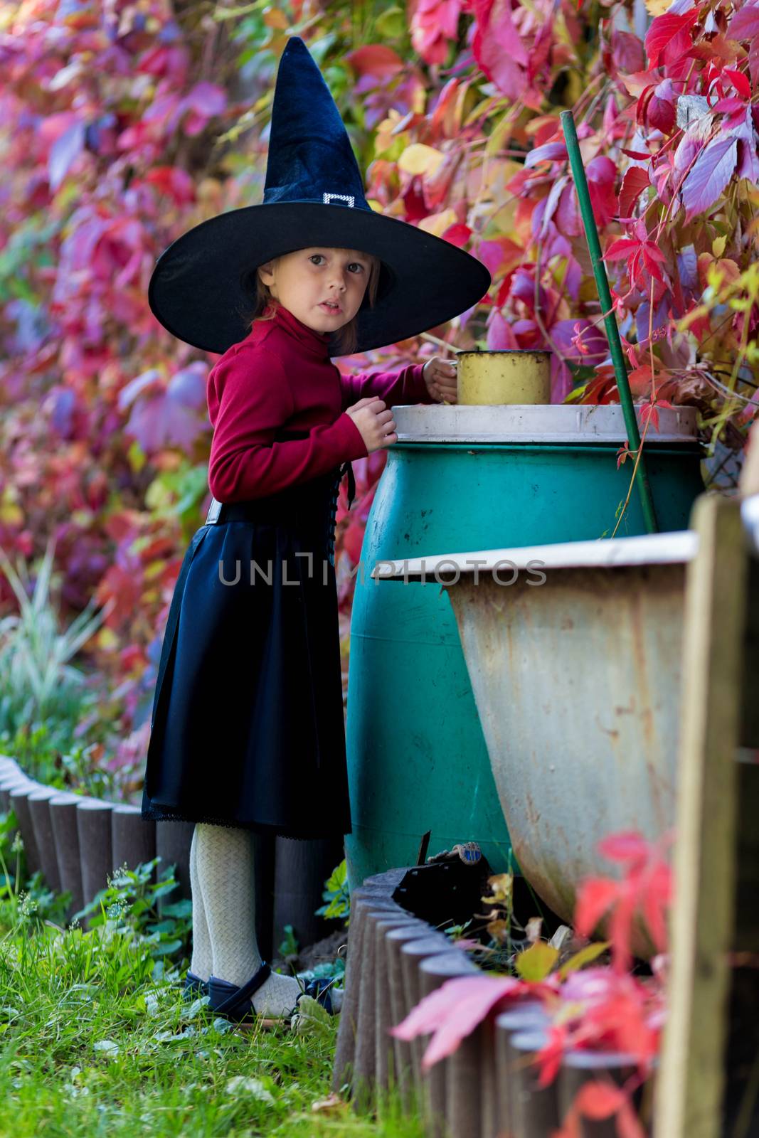 Little girl in a witch costume interferes with a potion on a halloween party by galinasharapova