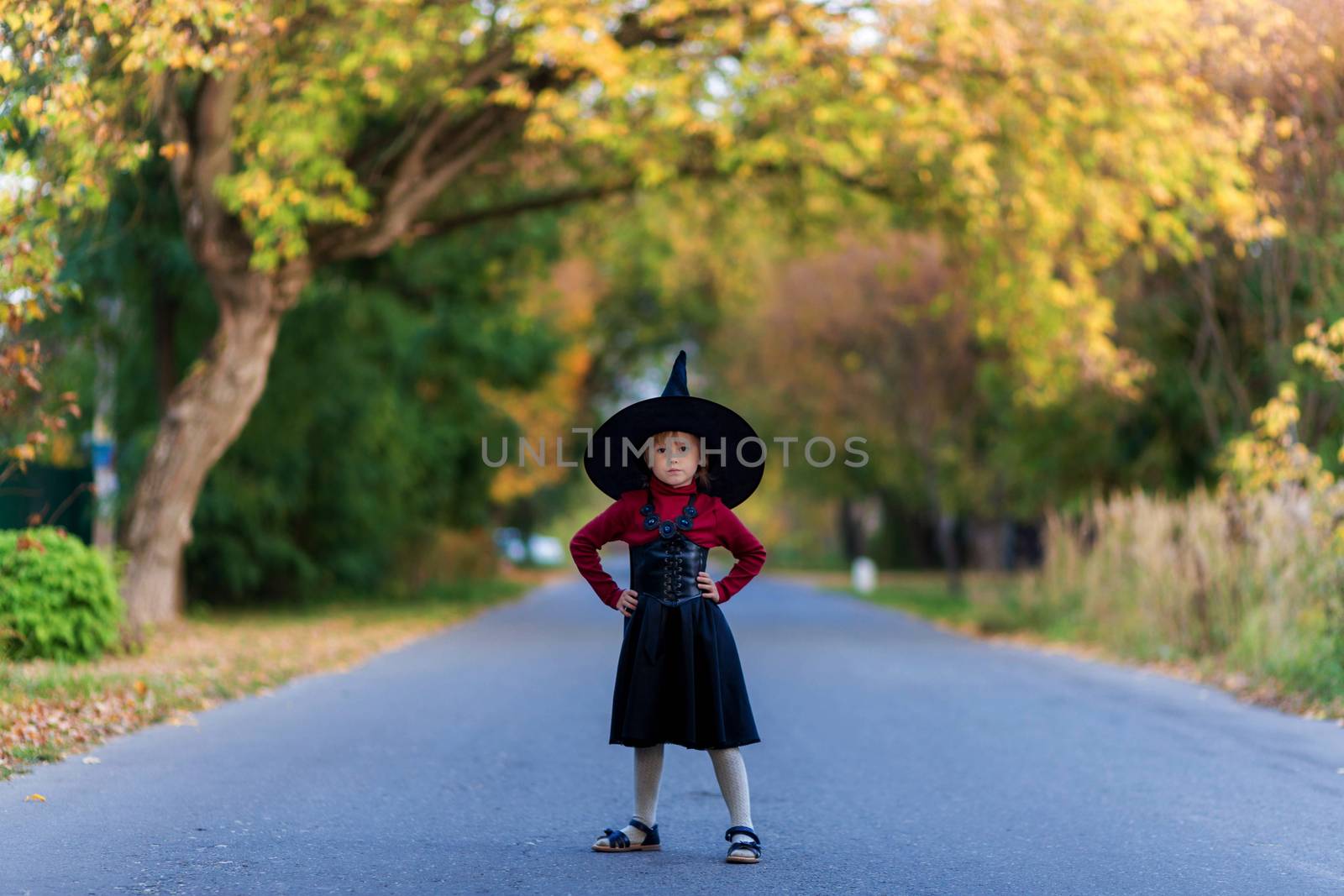 Little girl in a witch costume stands on the road on a halloween party by galinasharapova